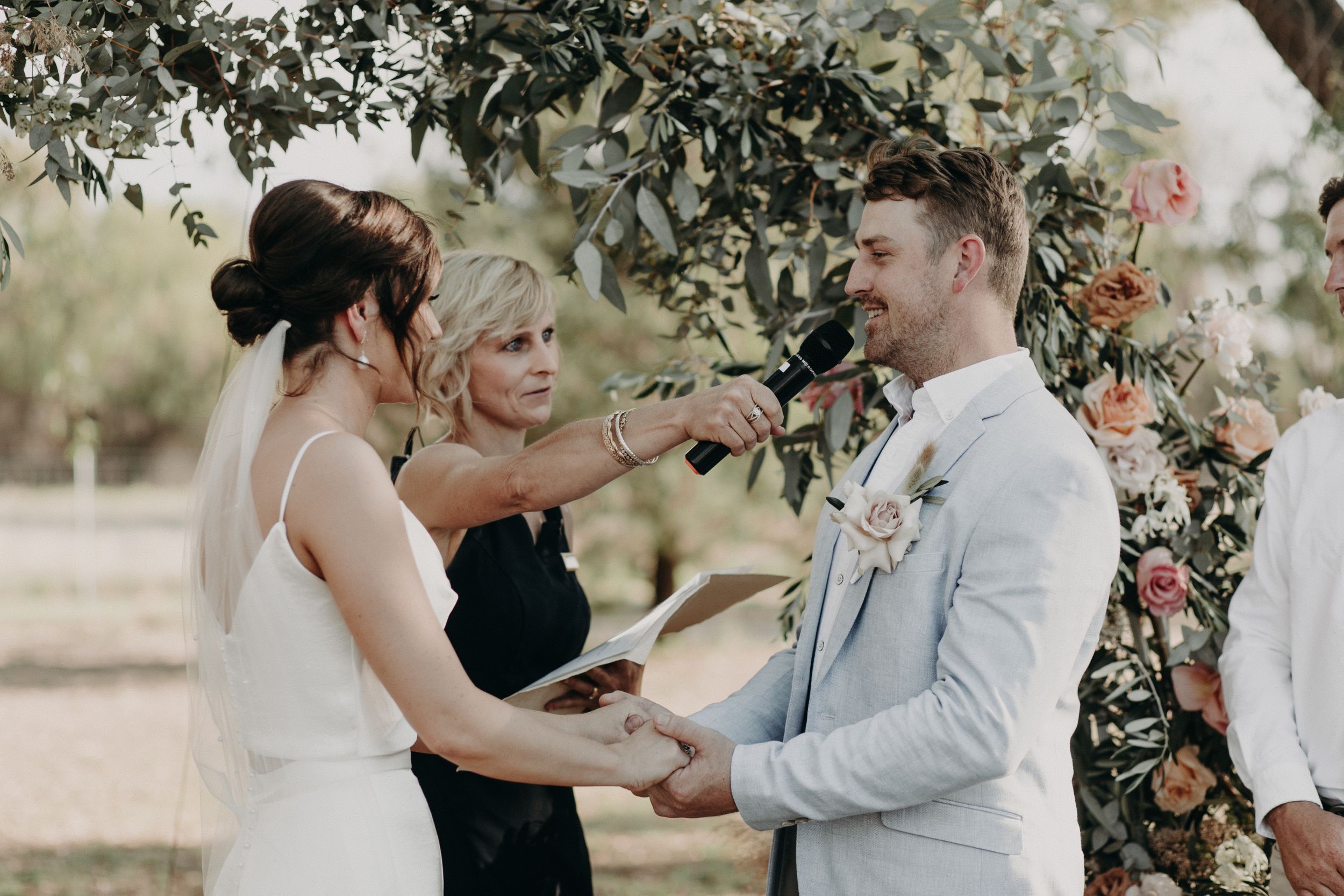 Intimate wedding ceremony moments captured under blooming trees in natural lighting.