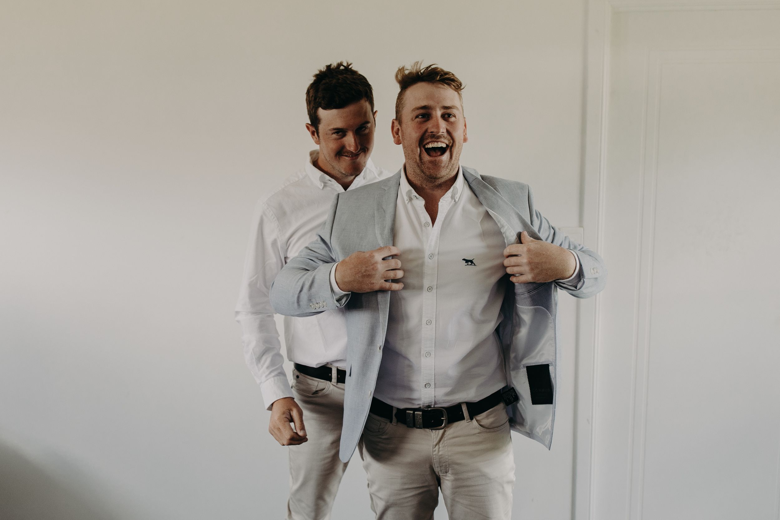 Two people in formal attire adjusting clothing and accessories before a special event.