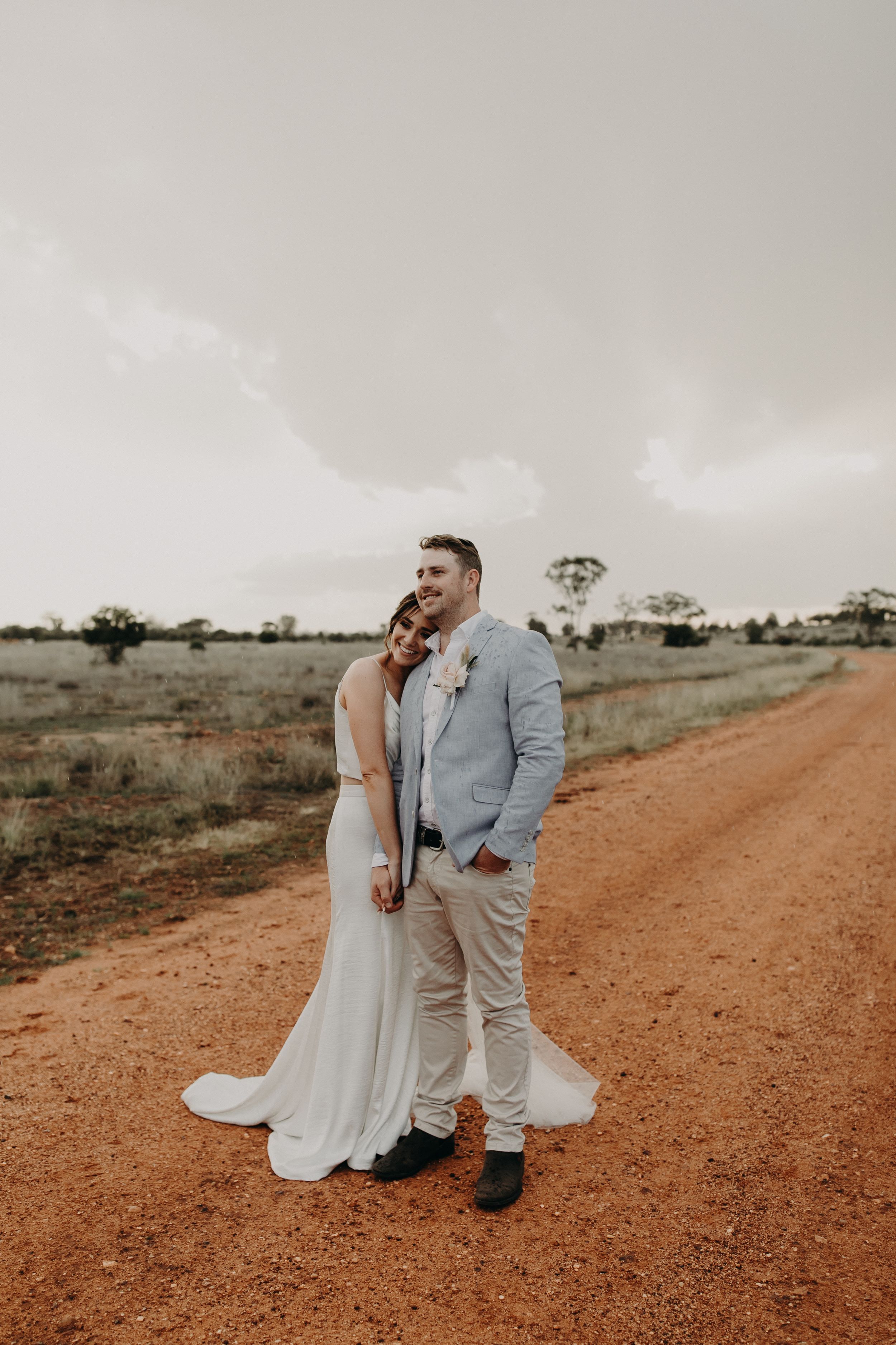 Newlyweds share tender moments on an outback dirt road.