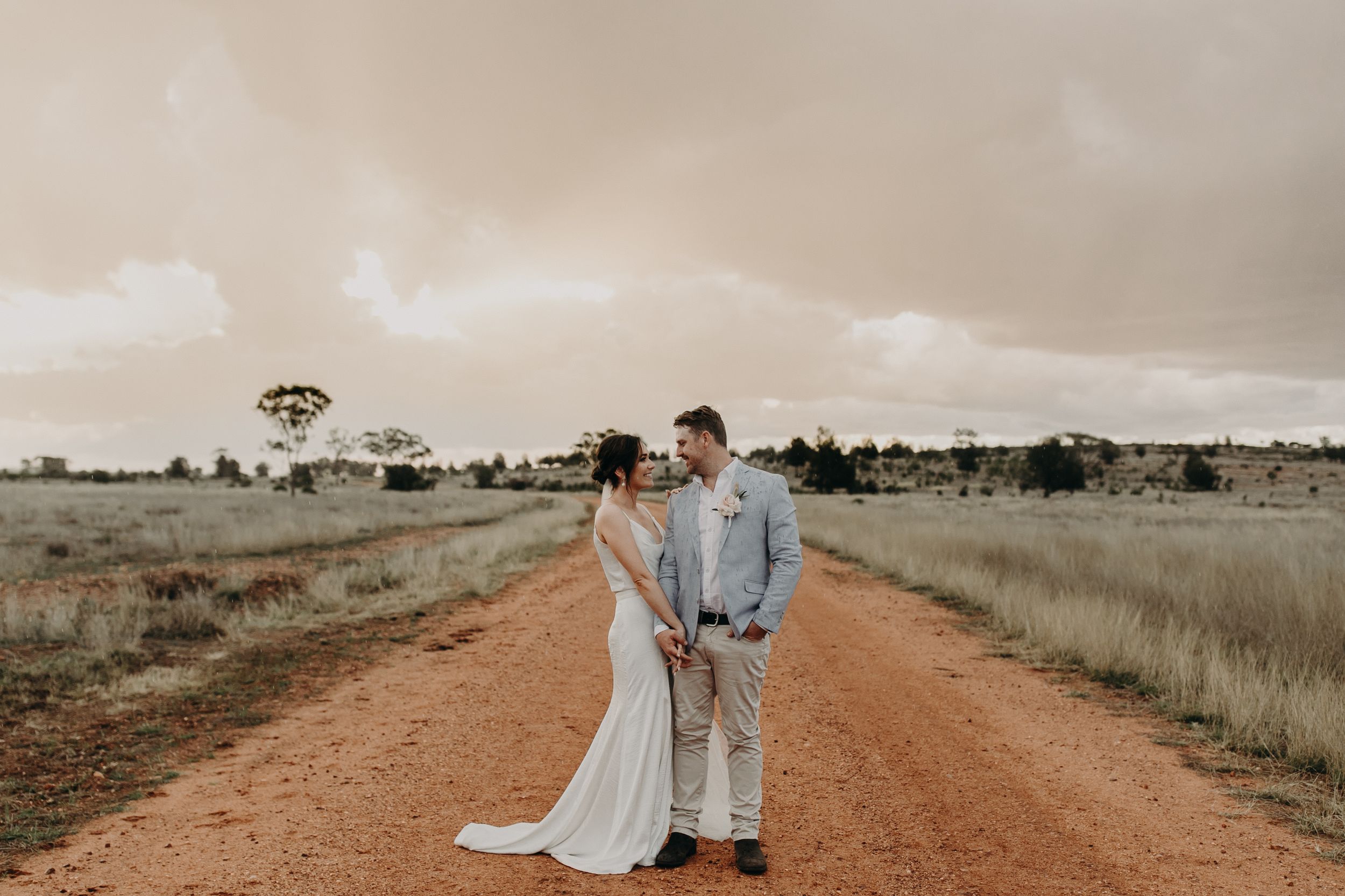 Intimate wedding portraits captured on a remote country road under cloudy skies.