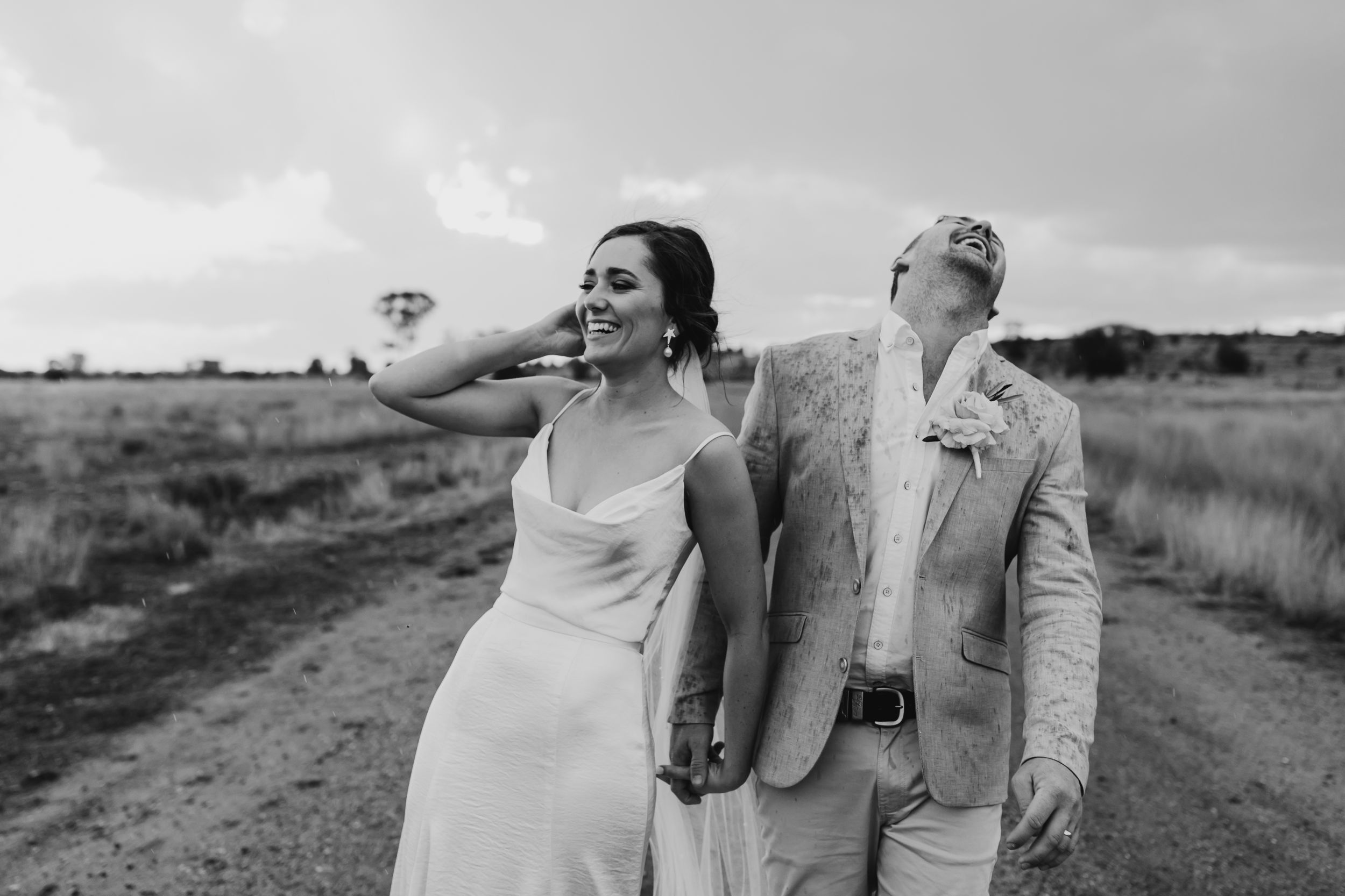 A couple shares a joyful moment on a country dirt road with a hot air balloon in the background.