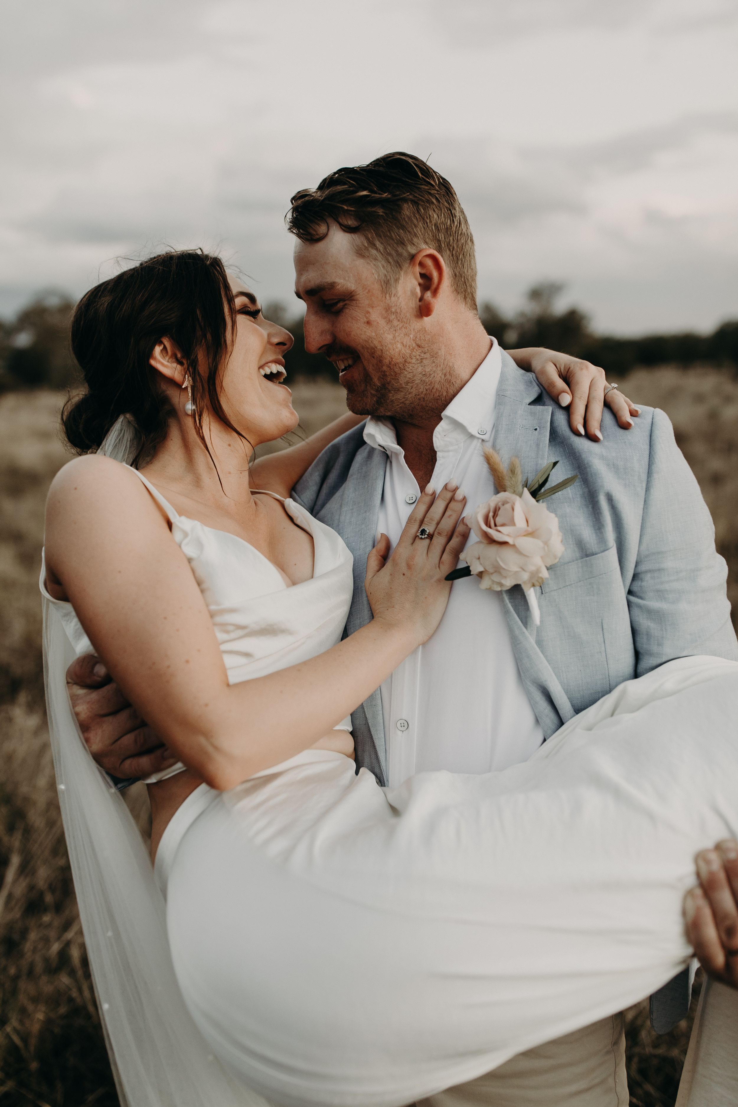 A romantic wedding photo captured in a rustic field with soft natural lighting.