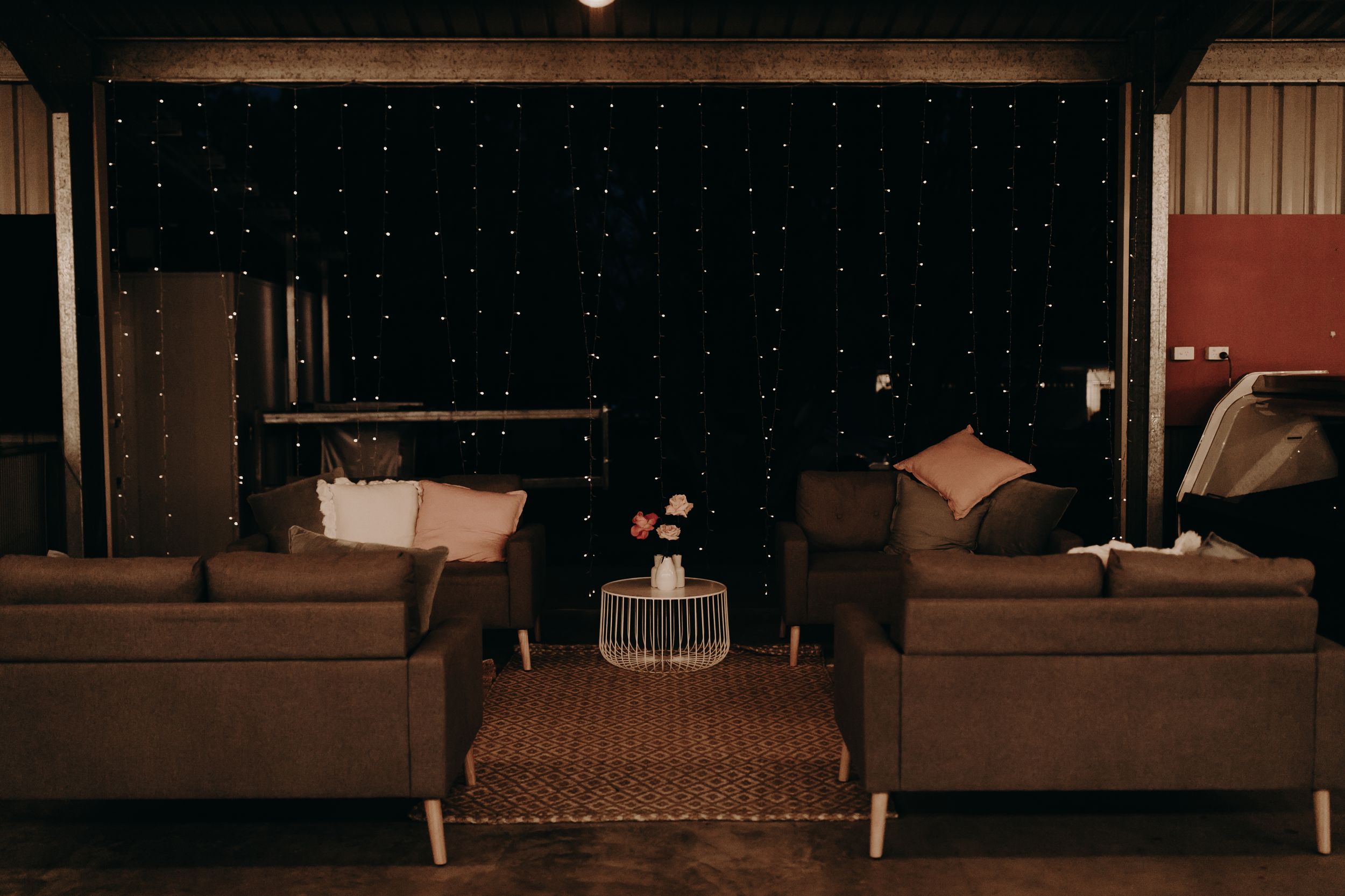 Cozy lounge area with brown couches and twinkle light backdrop.