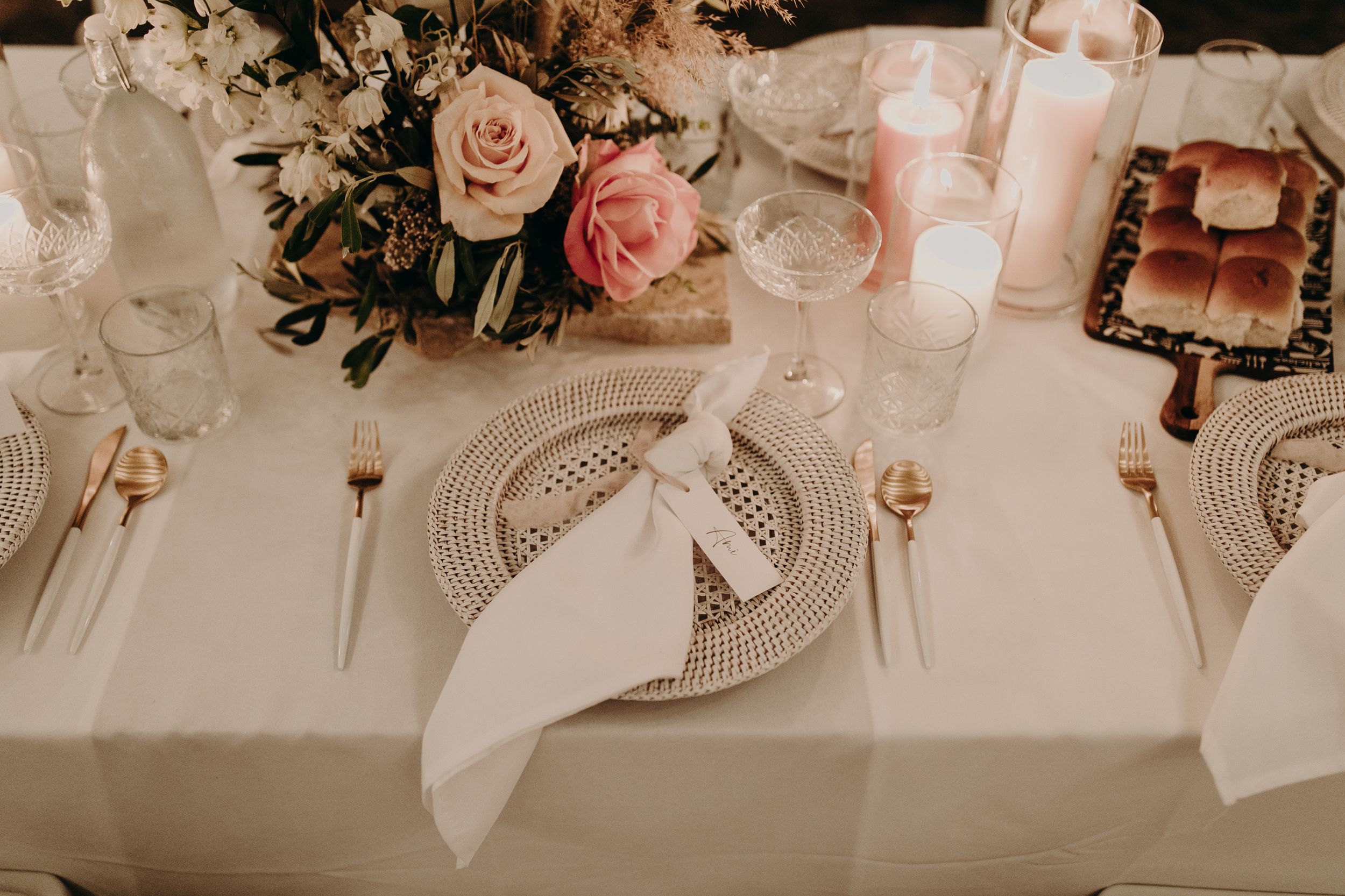 Close-up of wedding table settings with pink floral arrangements and crystal glassware.