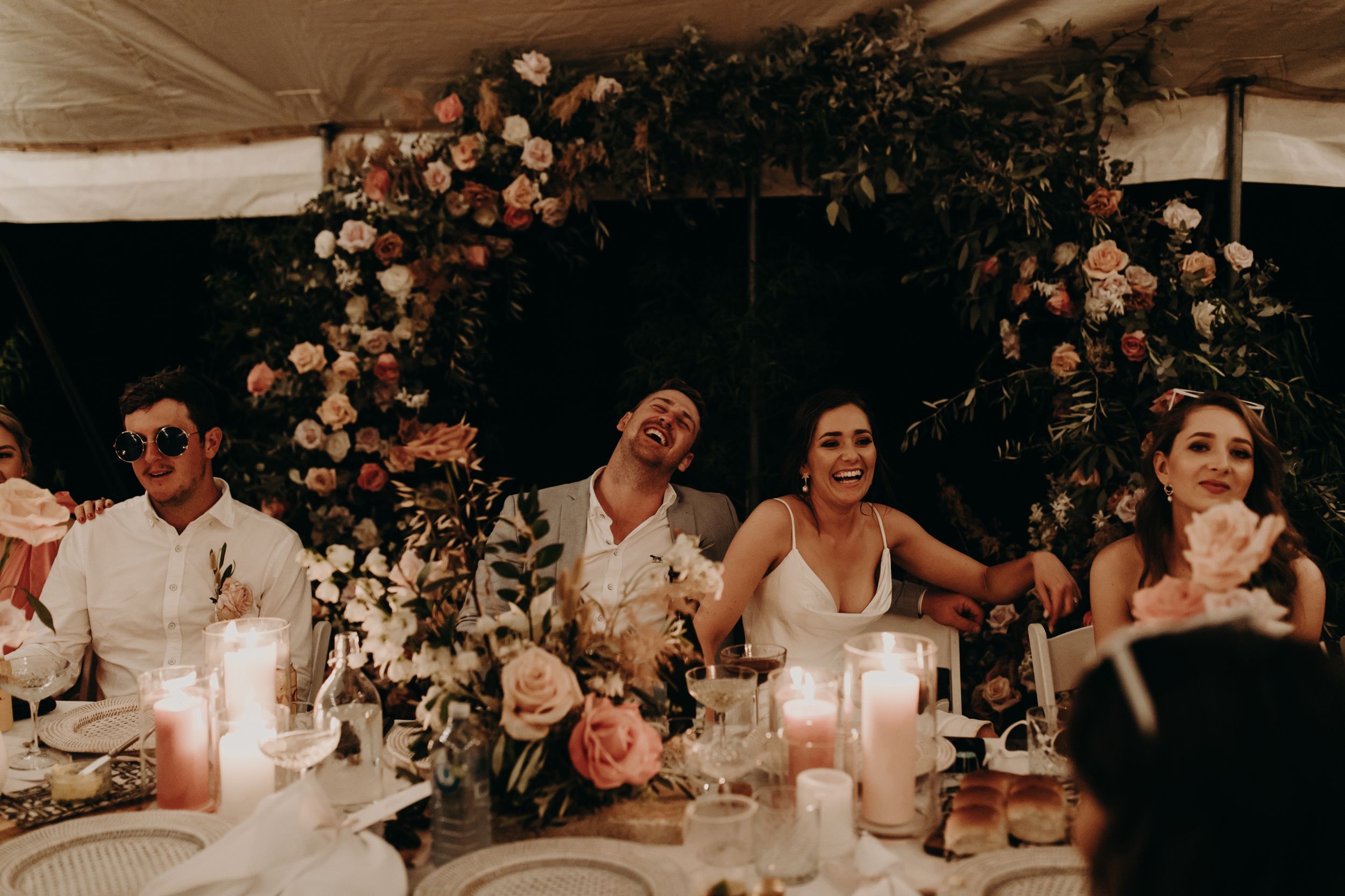 Wedding reception table decorated with candlelight and floral arrangements.
