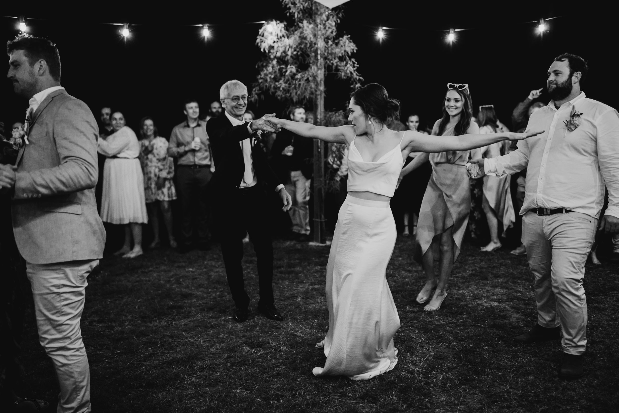 Wedding guests dancing and celebrating at a lively outdoor evening reception.