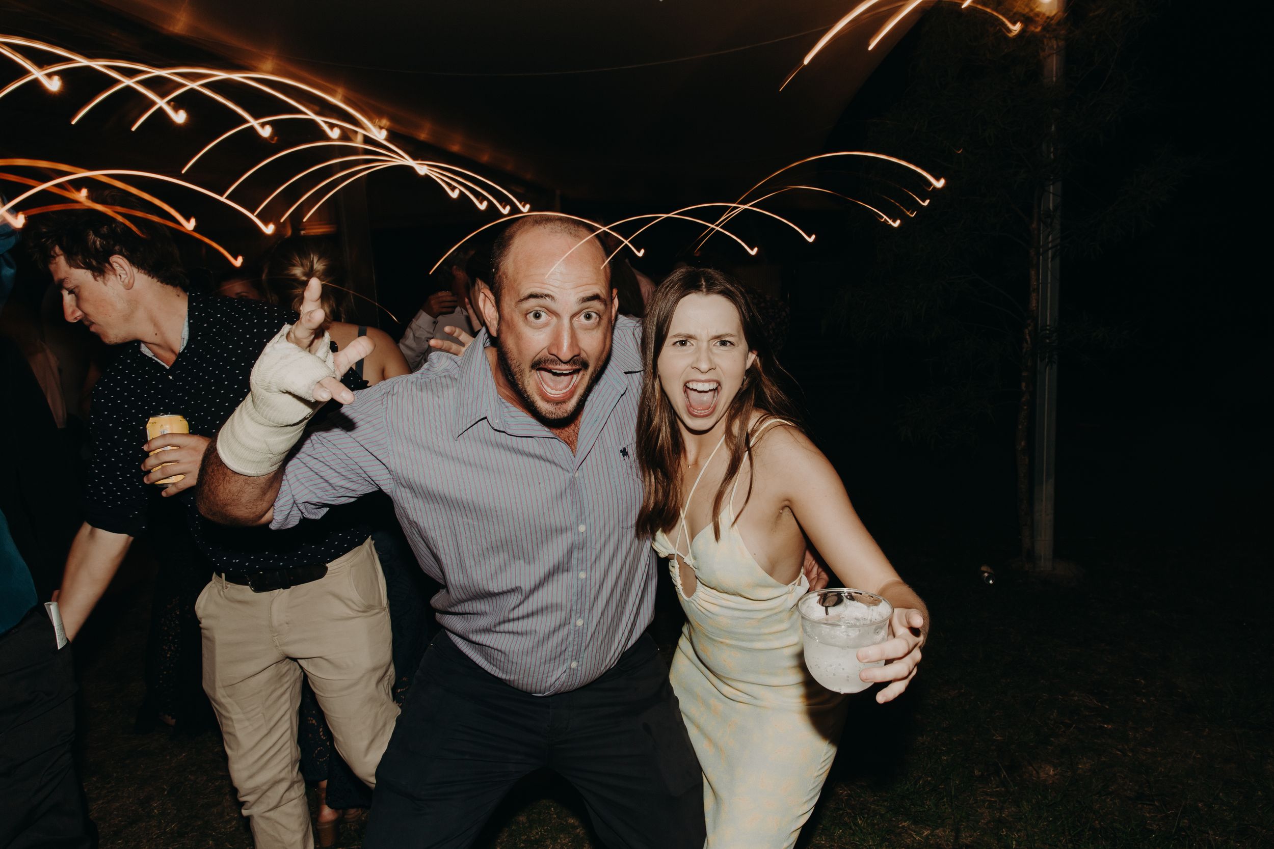 Wedding guests dancing and celebrating with light trails creating dynamic motion effects.