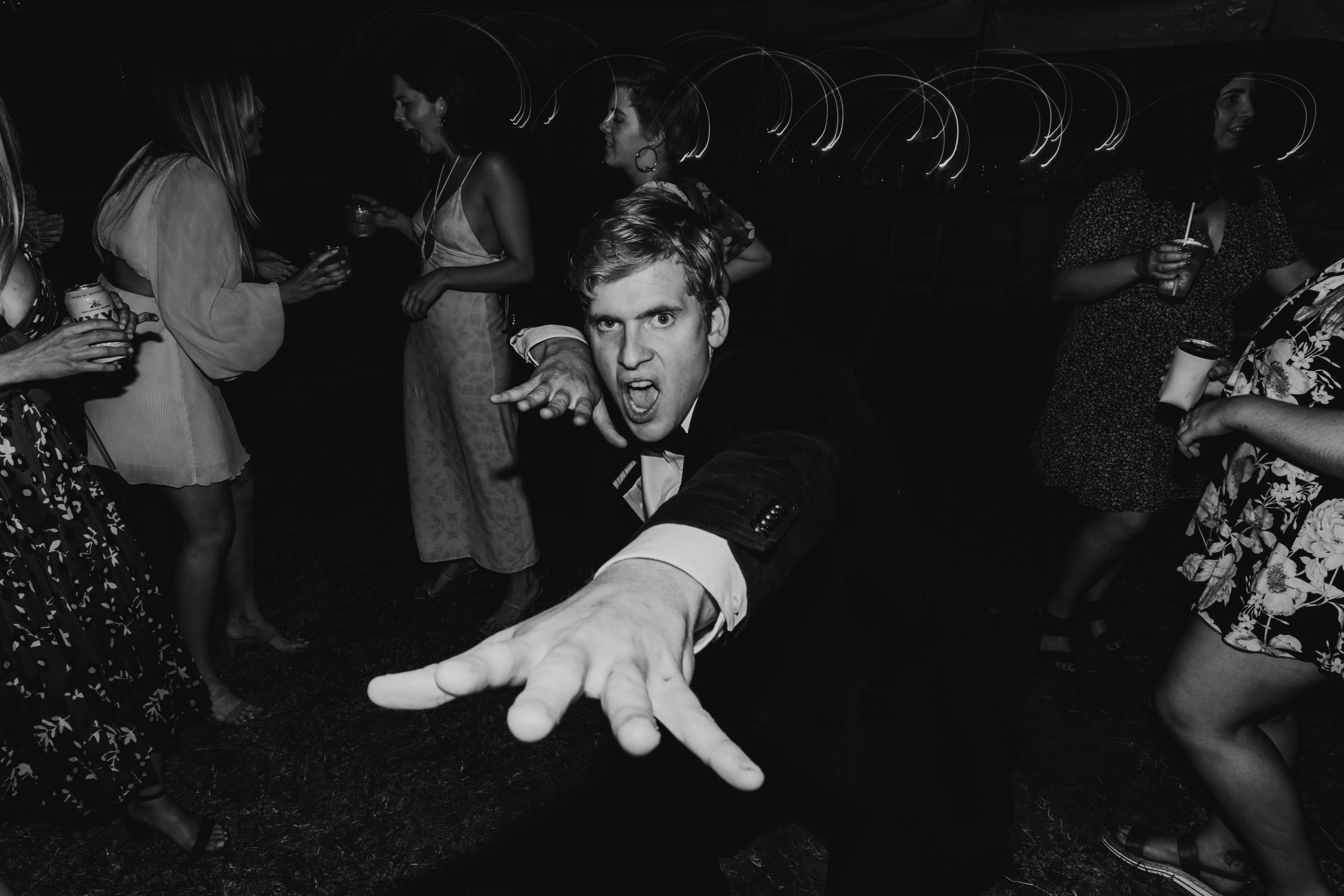 Wedding guests dancing and celebrating at a lively reception party in black and white.