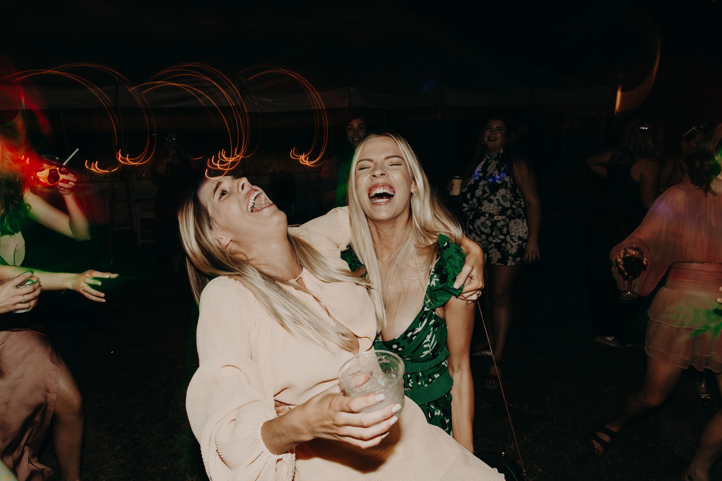 Candid moments of joy and laughter captured at a wedding party in dark lighting.