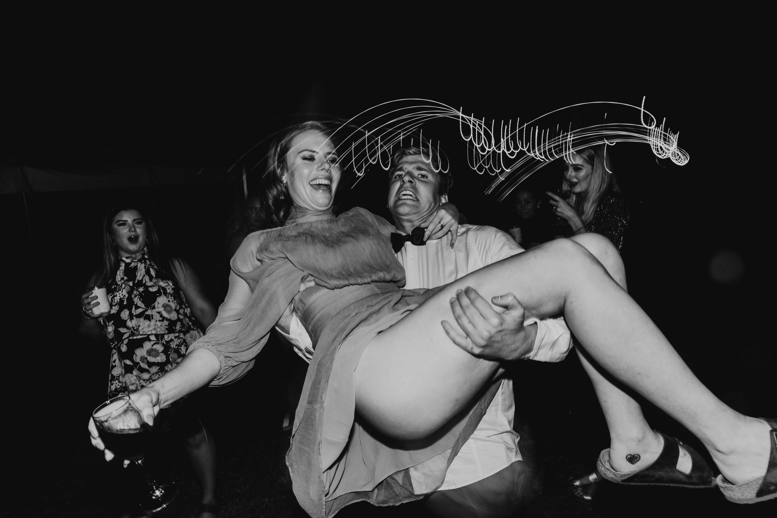 Black and white photo of energetic dancing and celebration at a wedding reception.