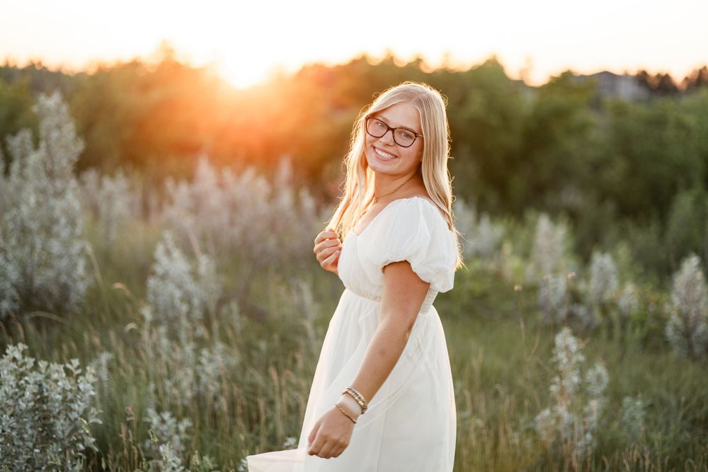 Person in white summer dress standing in field at golden hour.