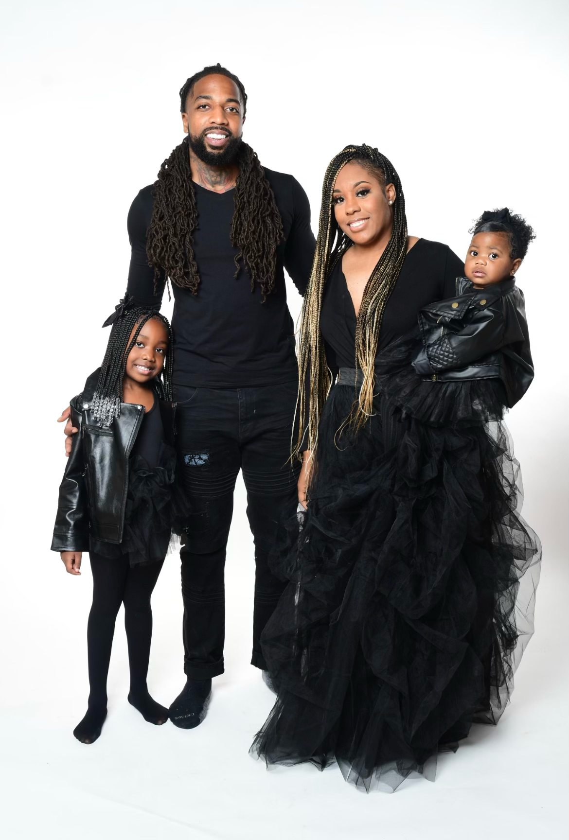 A stylish family portrait in matching black outfits against a white background.