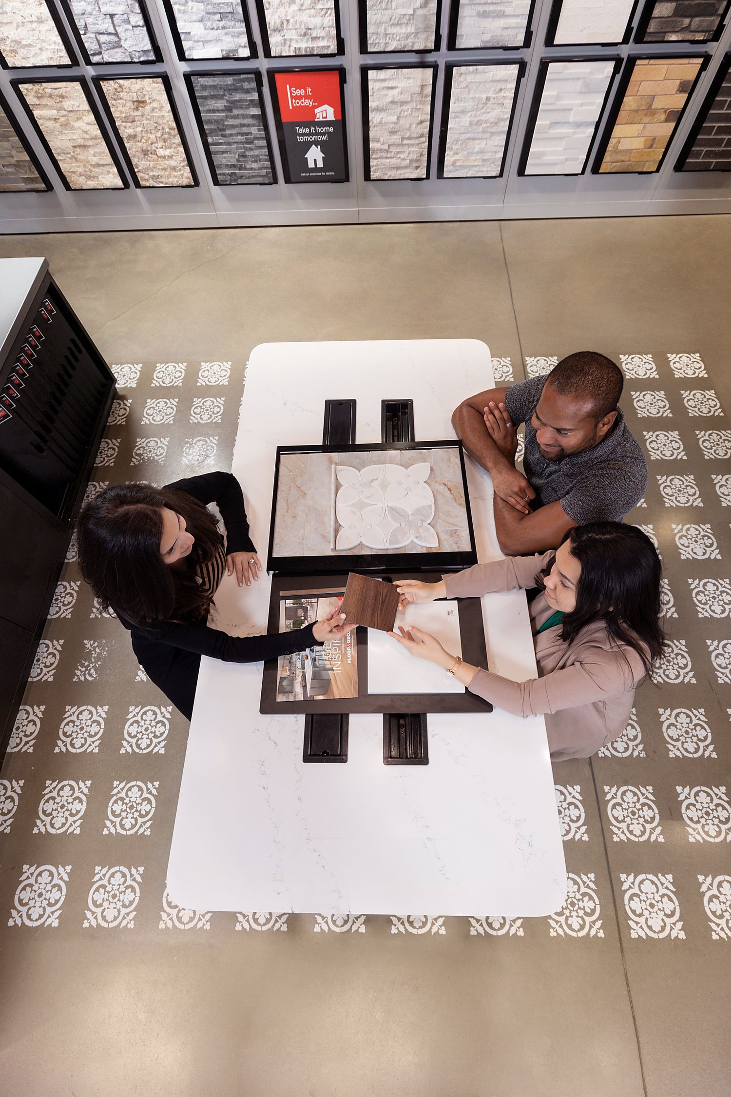 A young couple meets with a Floor & Decor designer to to review their product choices.