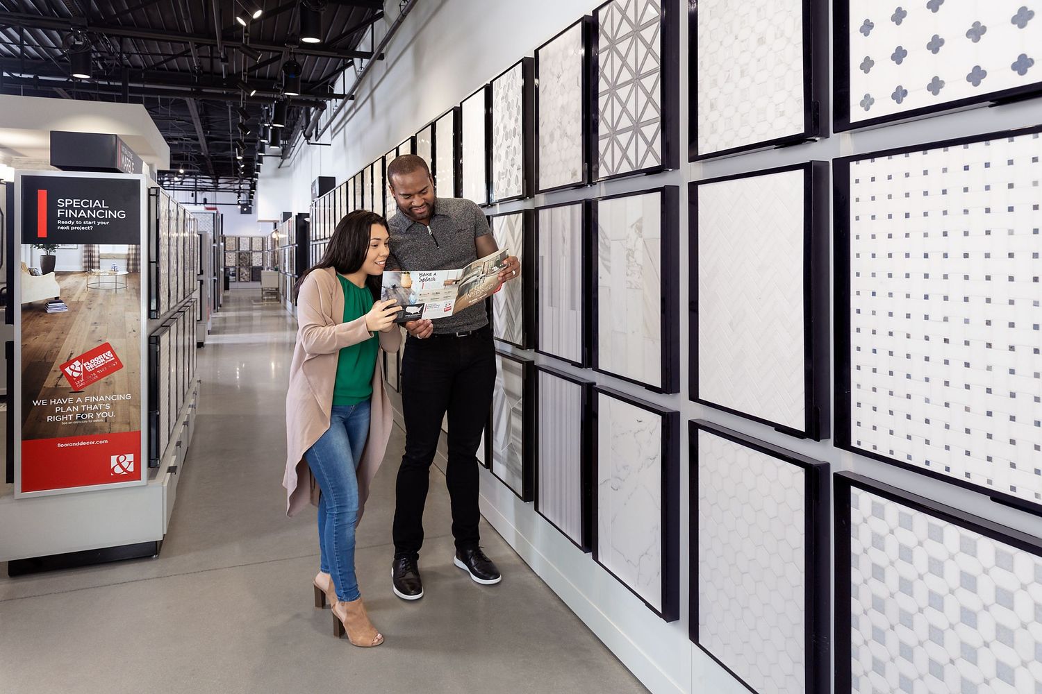 A young couple looks at a Floor & Decor product brochure while shopping for tile.