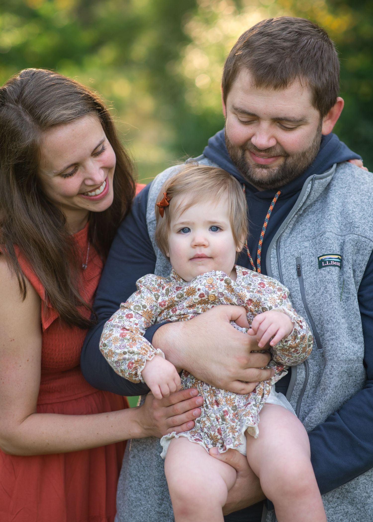 A joyful outdoor family portrait shows natural expressions and casual style.