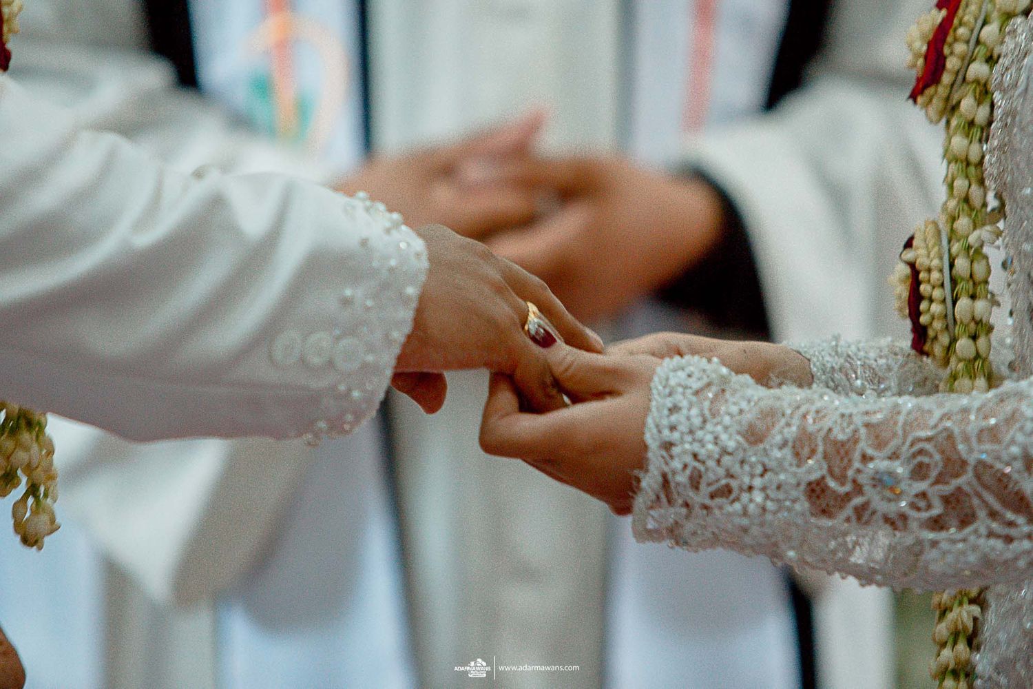 Detail shot of hands during ring exchange at traditional wedding ceremony.