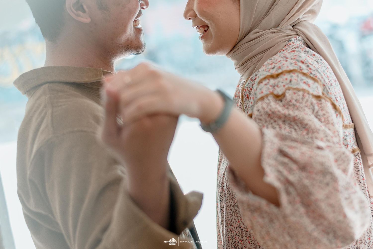 A candid moment captures a couple laughing together in soft natural light.