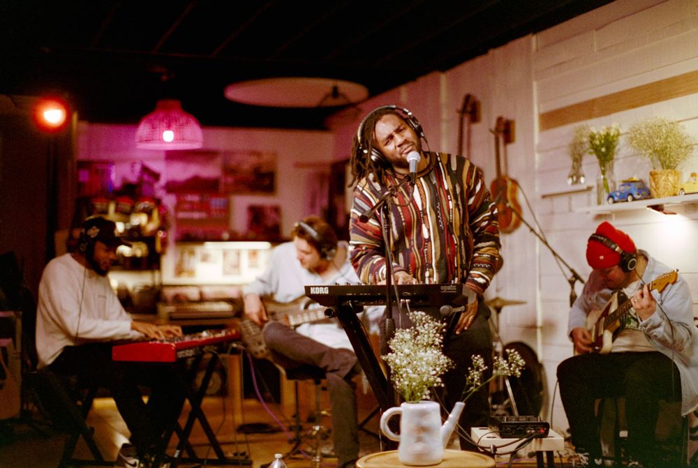 Musicians performing on stage with keyboards and instruments in a vintage-style setting.