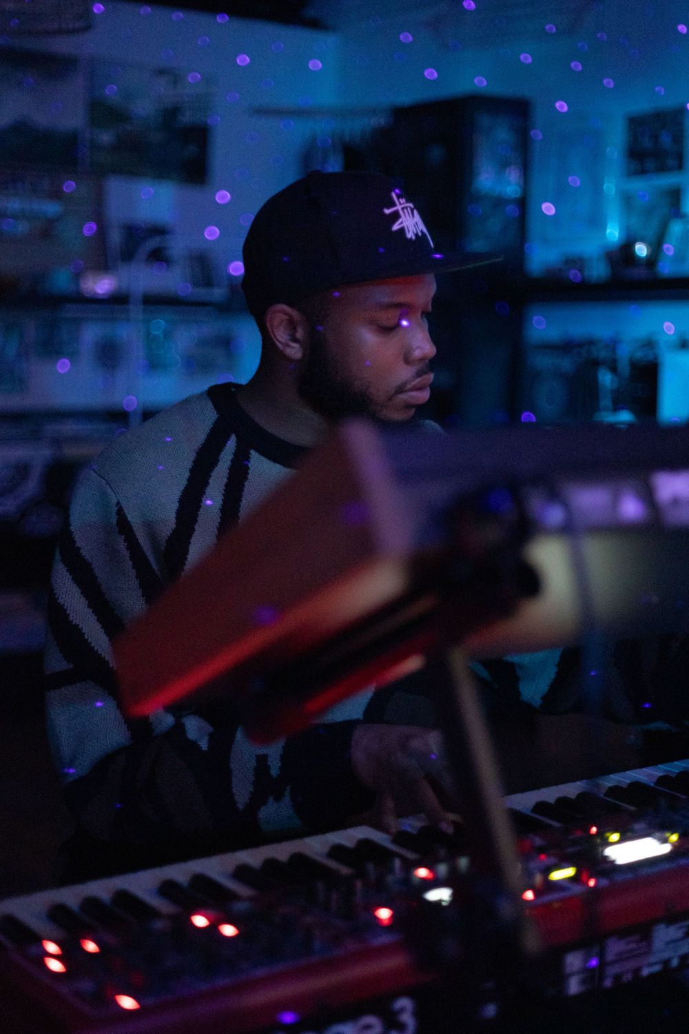 Keyboard player performing under moody purple and blue stage lighting.