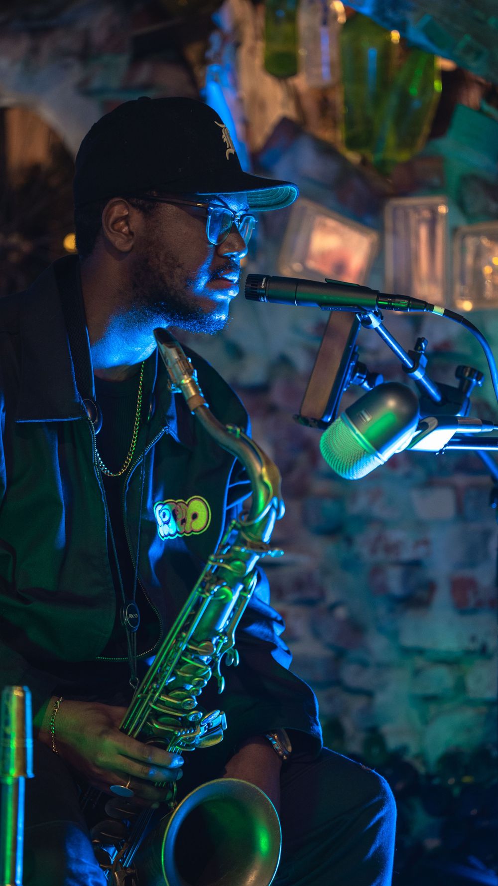 Saxophone player illuminated by blue stage lights performing with a microphone.
