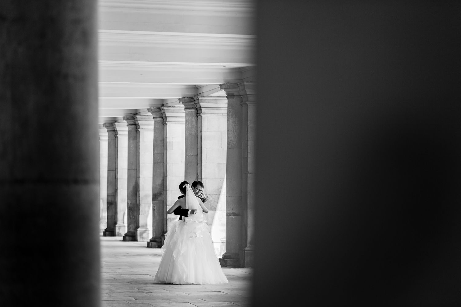 Wedding couple embrace in Cambridge cloisters