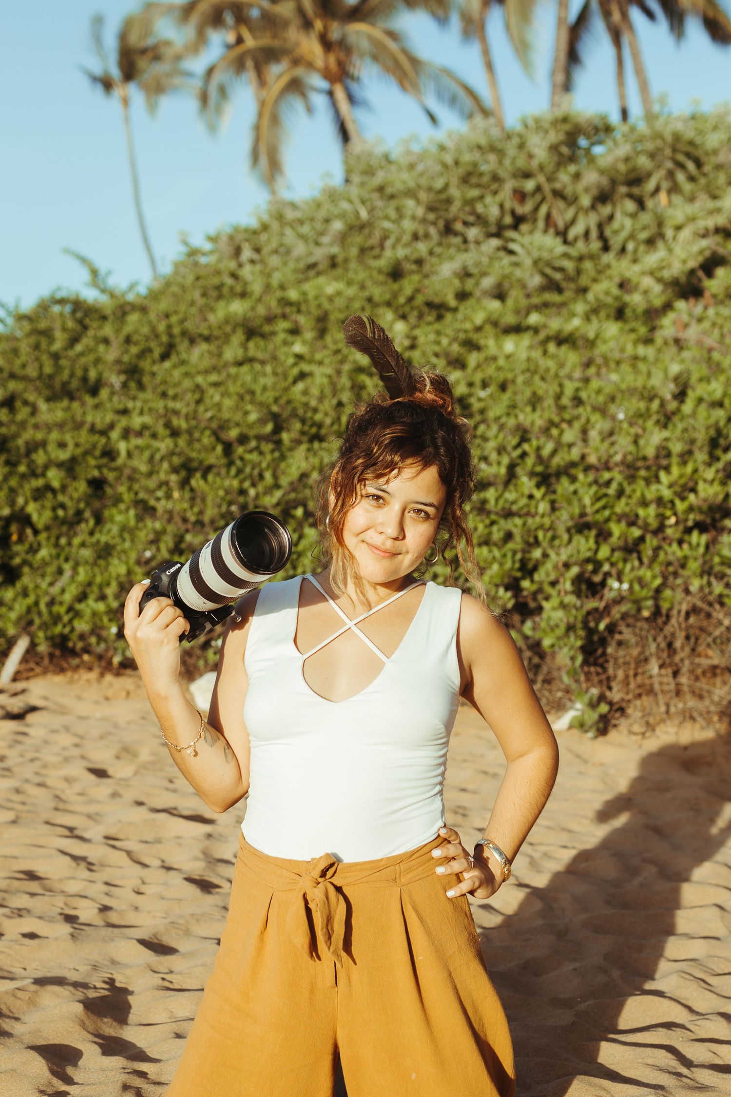 hawaii elopement photographer holds camera in her hand while at the hawaiian beach