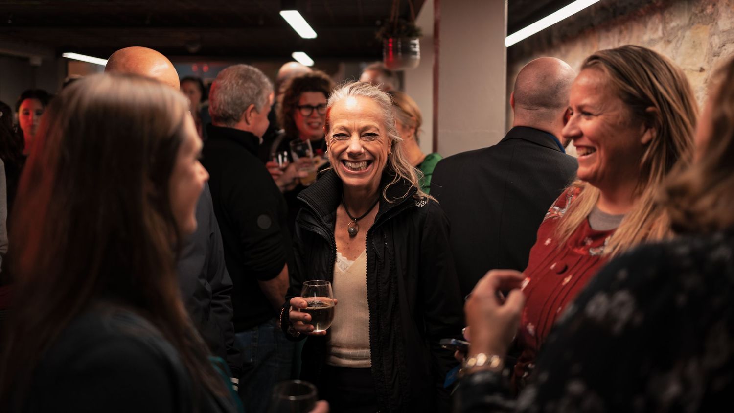 Guests laughing and socialising with drinks at a corporate networking event, candid corporate event photography