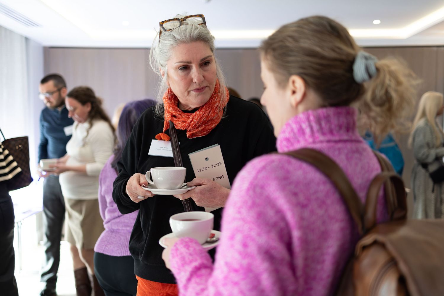 Two women chatting over coffee at a corporate networking event, candid business networking photography