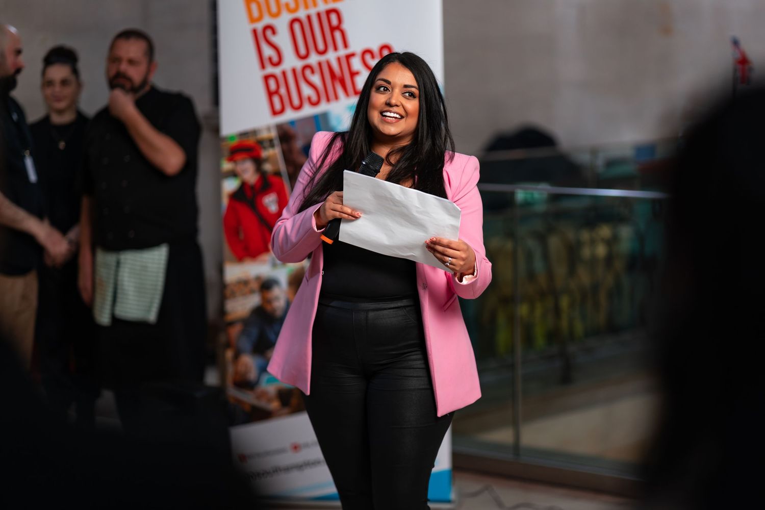 Award winner in pink blazer holding trophy at a business awards ceremony, corporate awards event photography