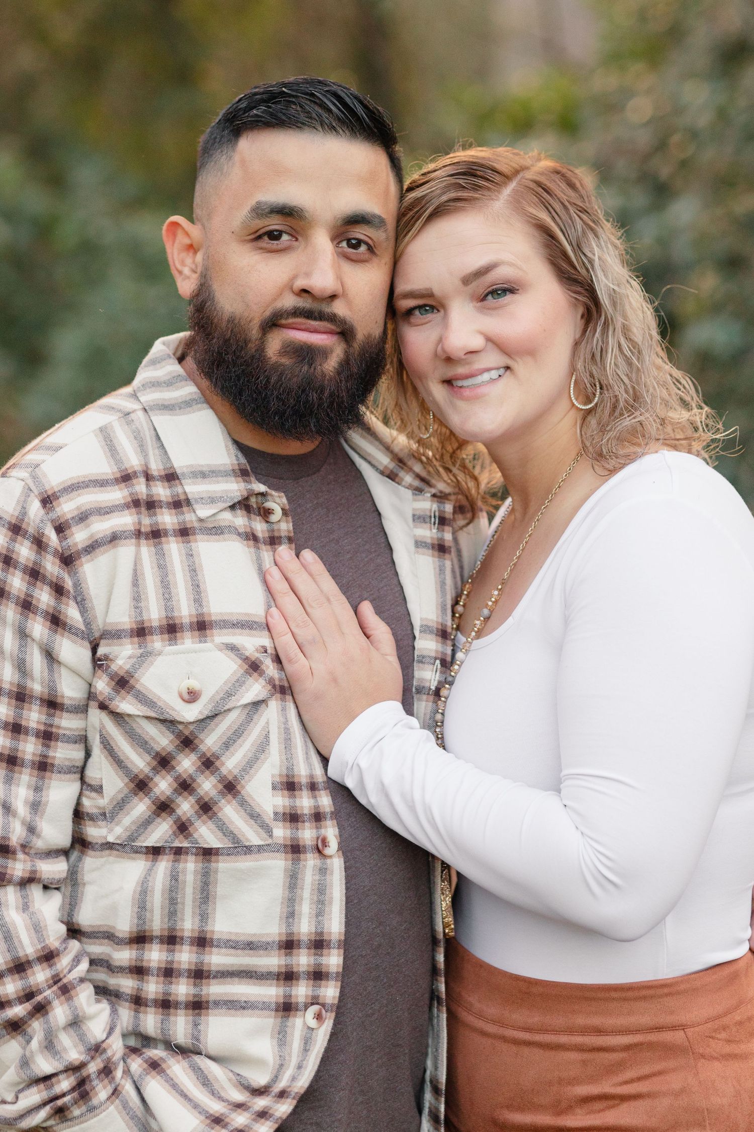 Couple shares an intimate moment while posing for a portrait outdoors.
