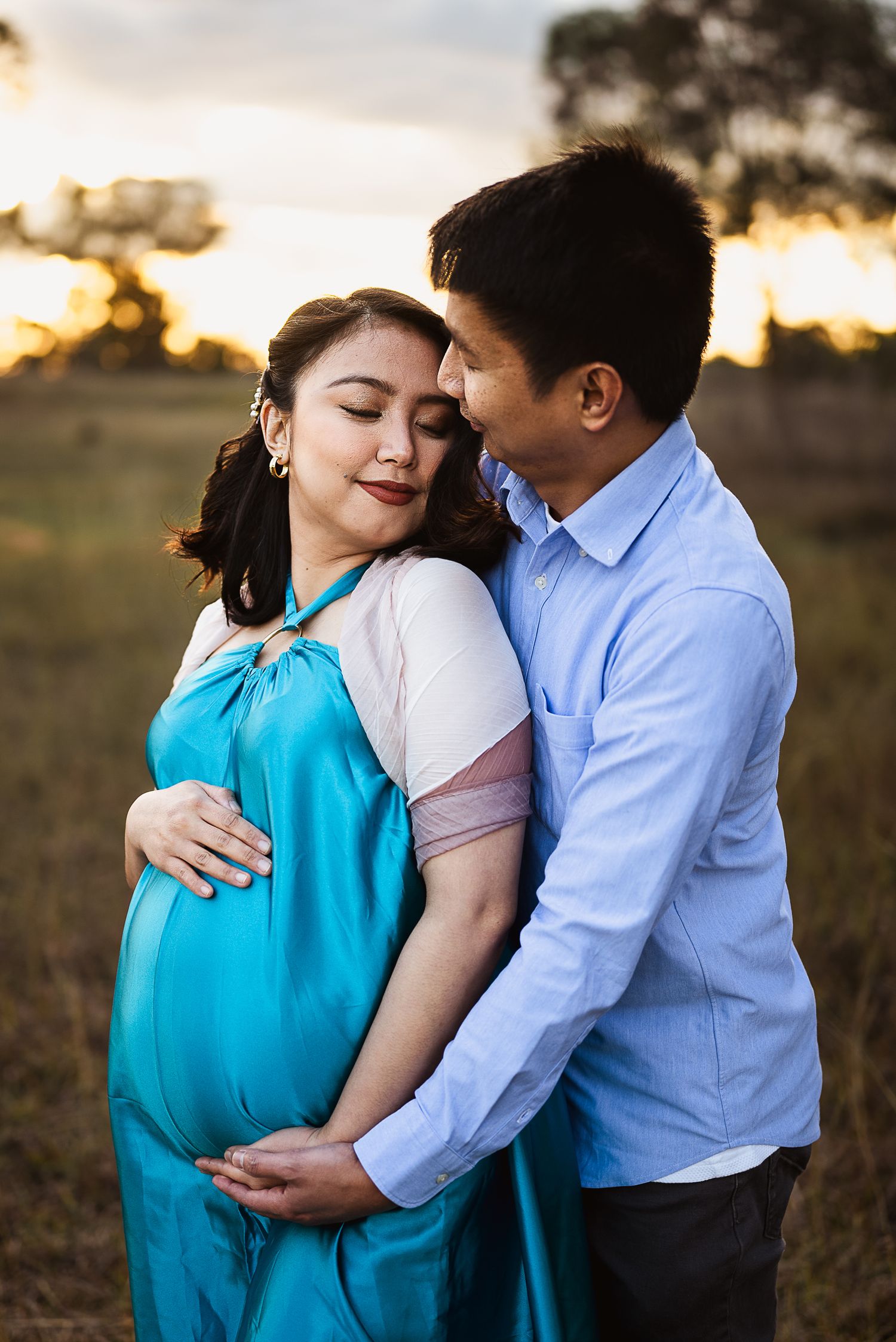 Couple holding each other at sunset holding their baby Dubbo Photographer