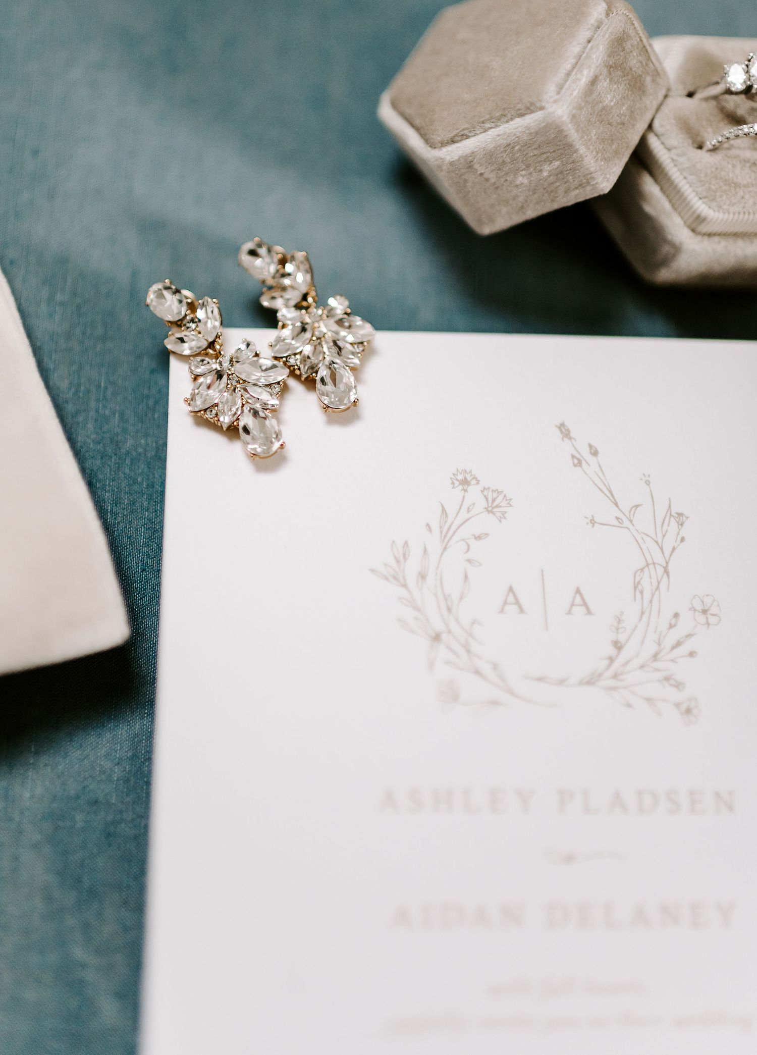 Minimalist wedding stationery with floral design elements displayed on teal background.
