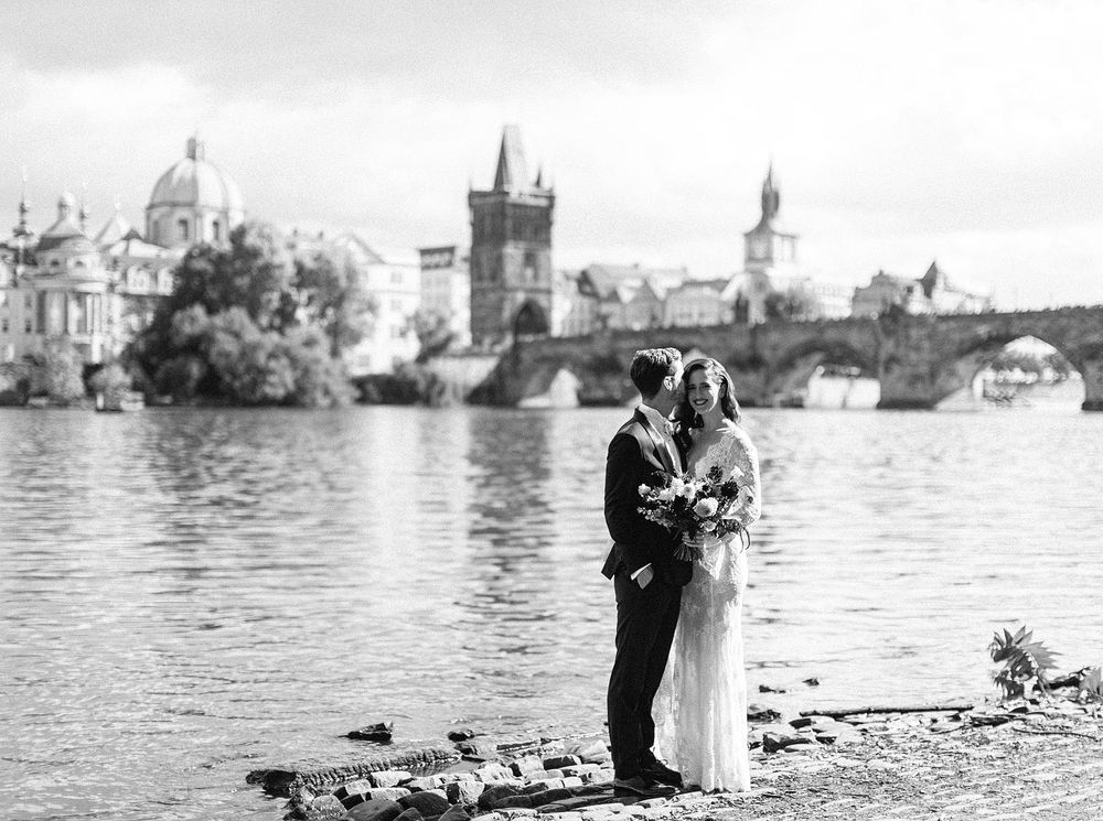 Bride and groom posing in front of Charles Bridge, Prague.