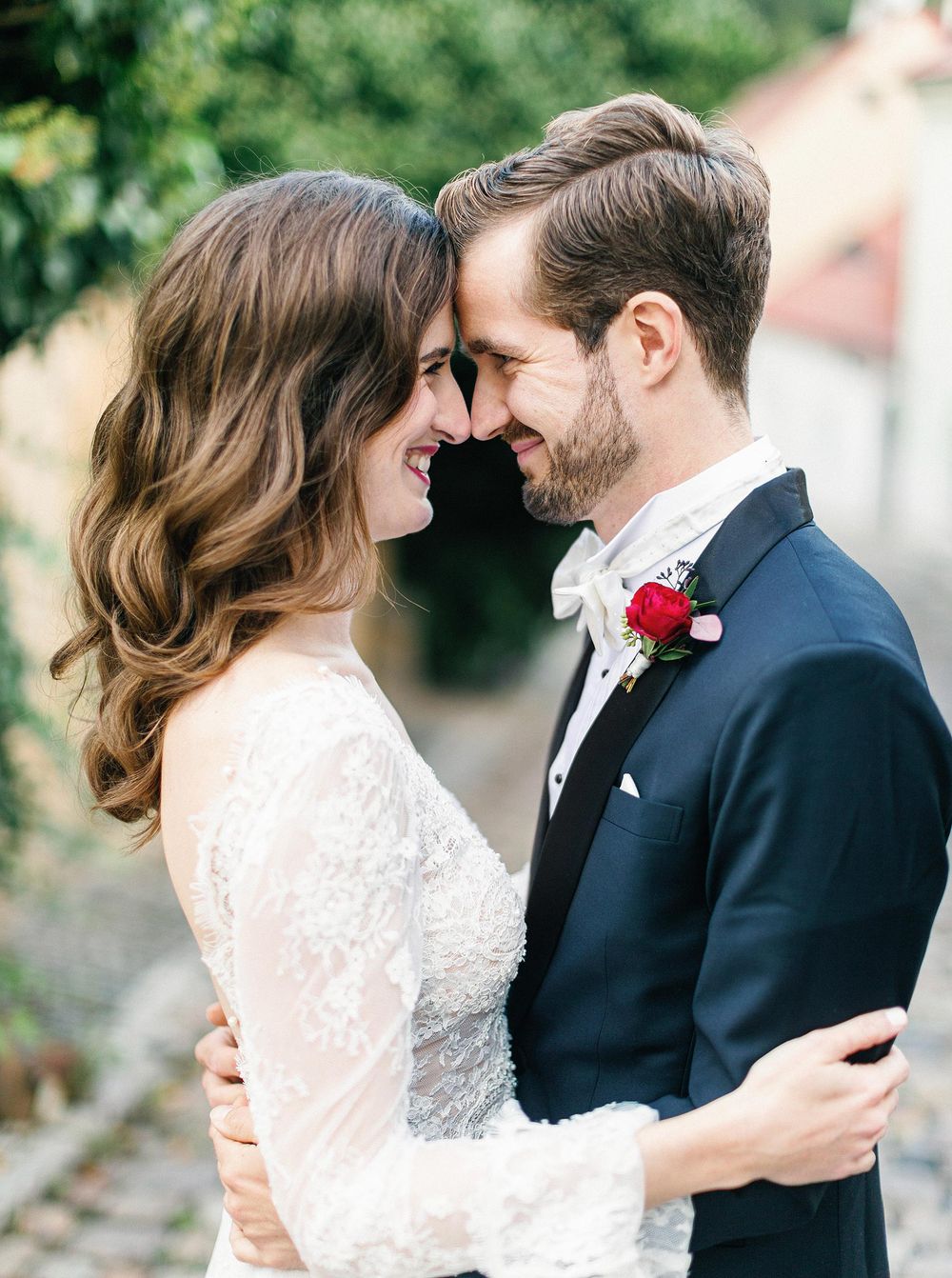Bride and groom smiling, standing close together in Prague, capturing a beautiful moment of their wedding day.
