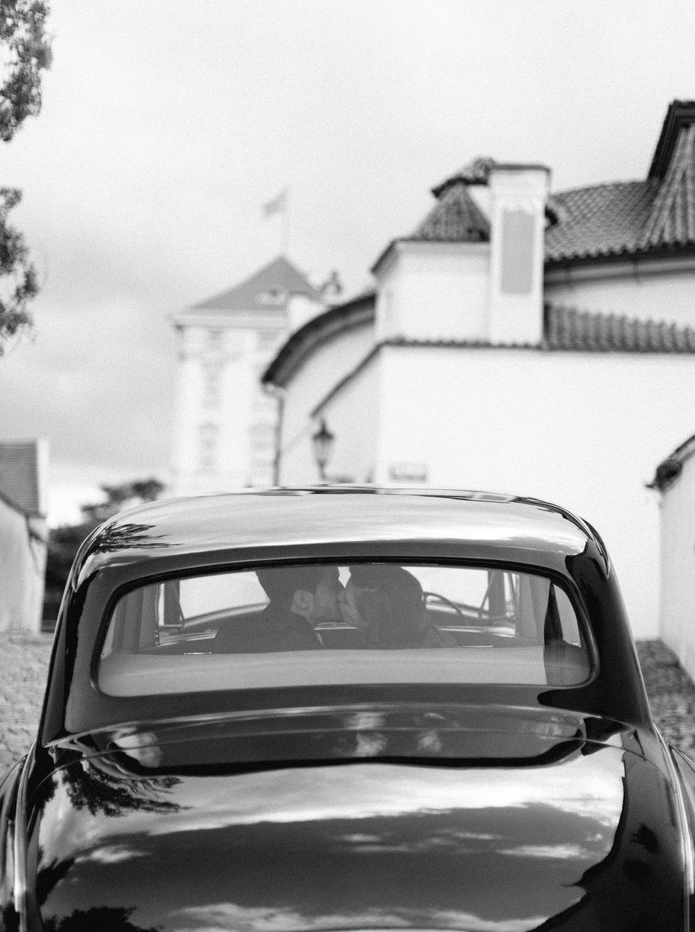 Newlyweds in a vintage Rolls Royce on a historic street in Prague.
