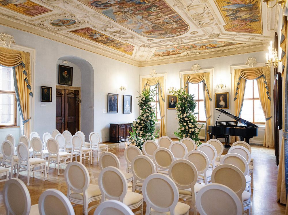 Wedding ceremony in Lobkowicz Palace, Prague: Elegant room with white chairs and a grand piano.