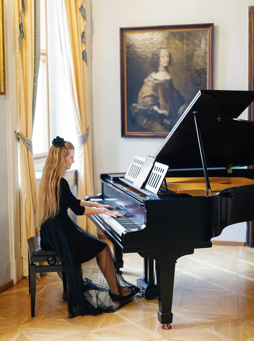 A woman gracefully playing a piano in a well-lit room, showcasing her musical talent and passion.