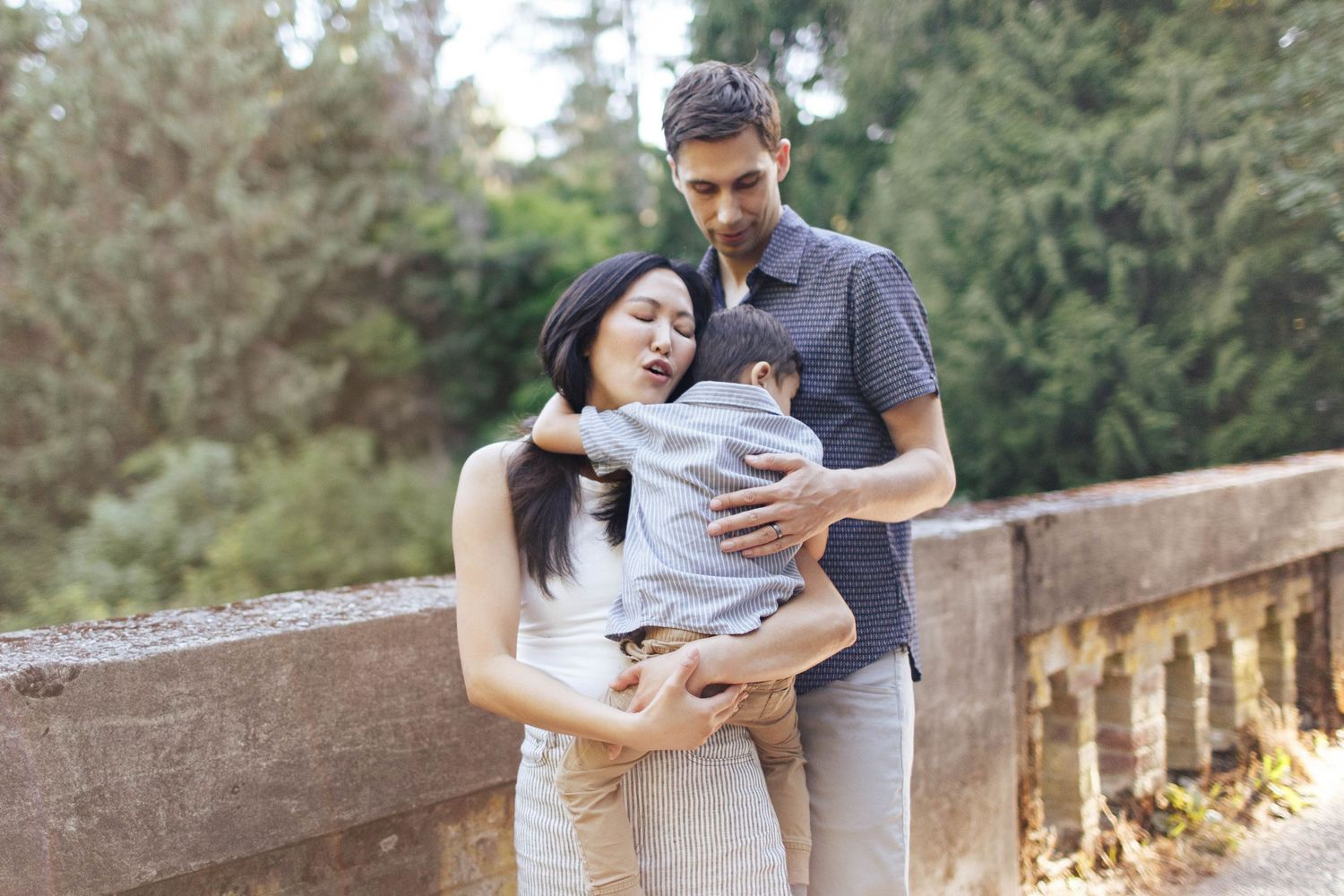 seattle family photographer: a mom is carrying and hugging her son while the dad looks over holding them