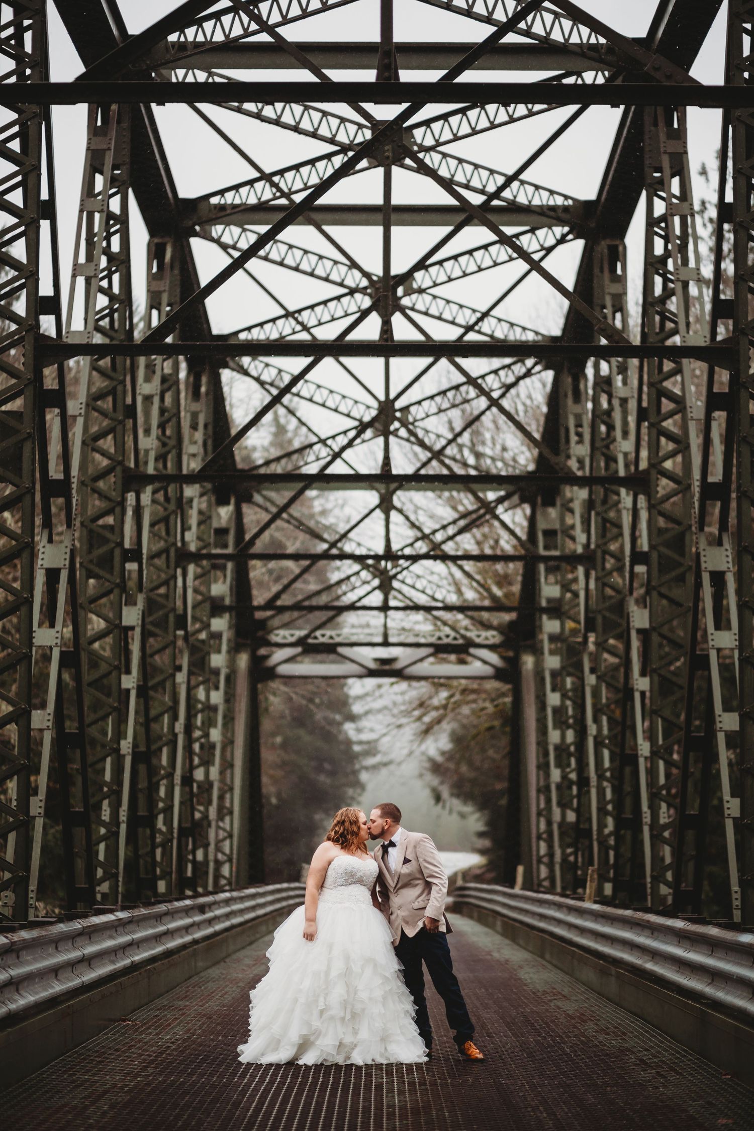 A bride and groom kiss on a steel bridge at their mountain elopement in Washington.