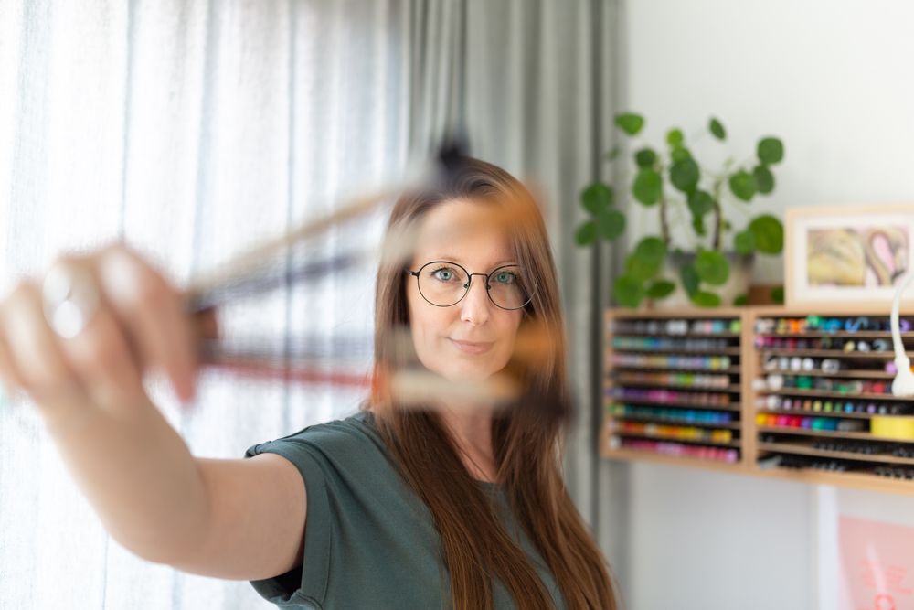 Motion blur capture of pasta making process with craft supplies visible in background.
