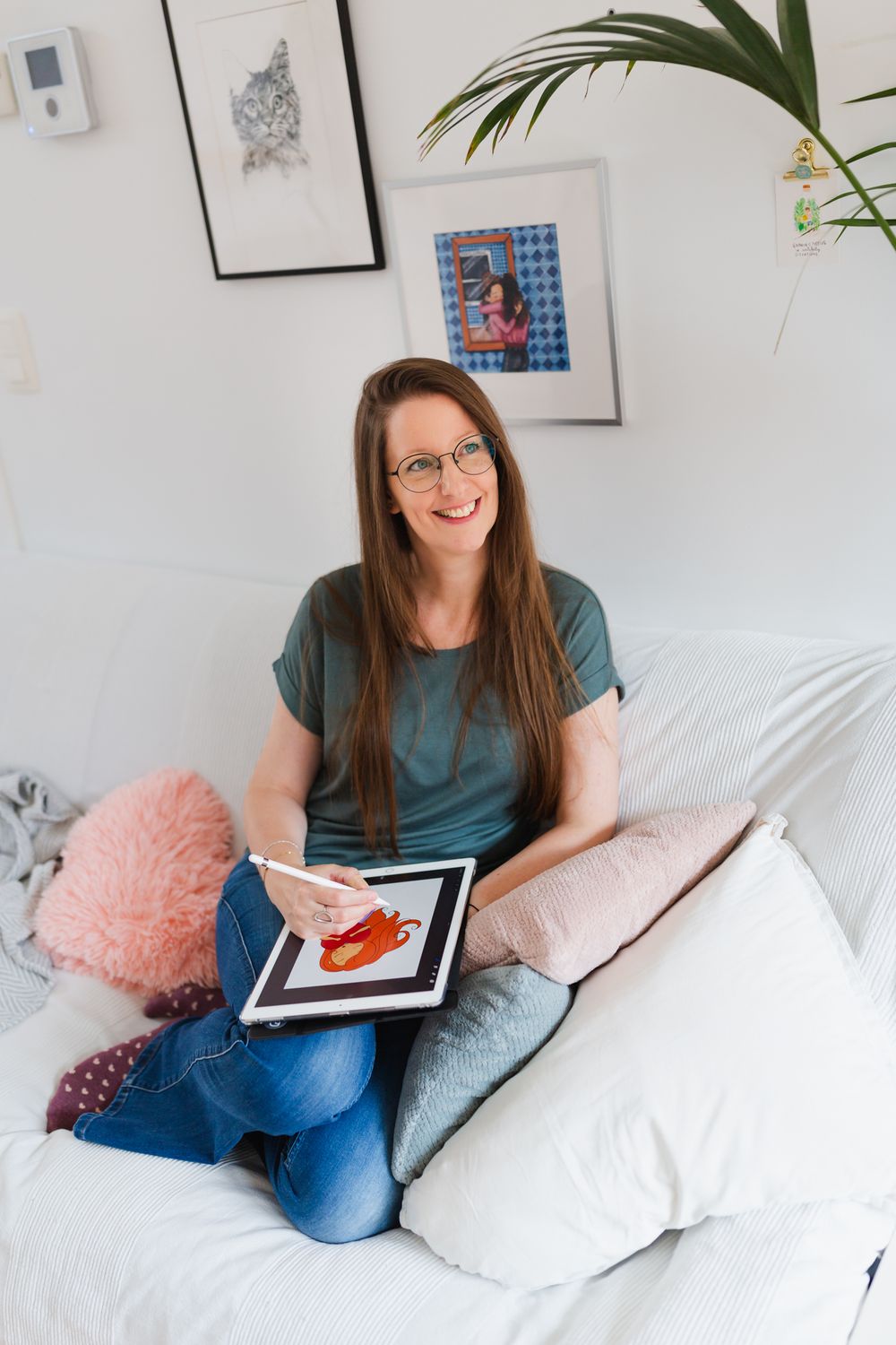 Cozy home workspace with artwork, plants and decorative pillows.