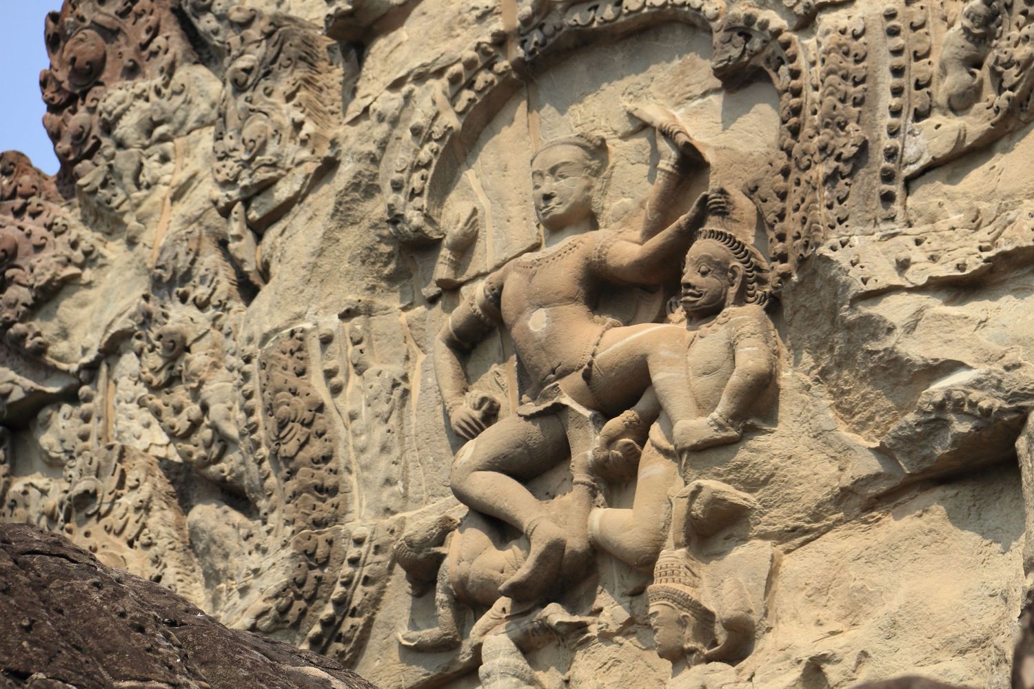 Ancient stone carving depicting intricate figures in traditional Asian architectural detail.