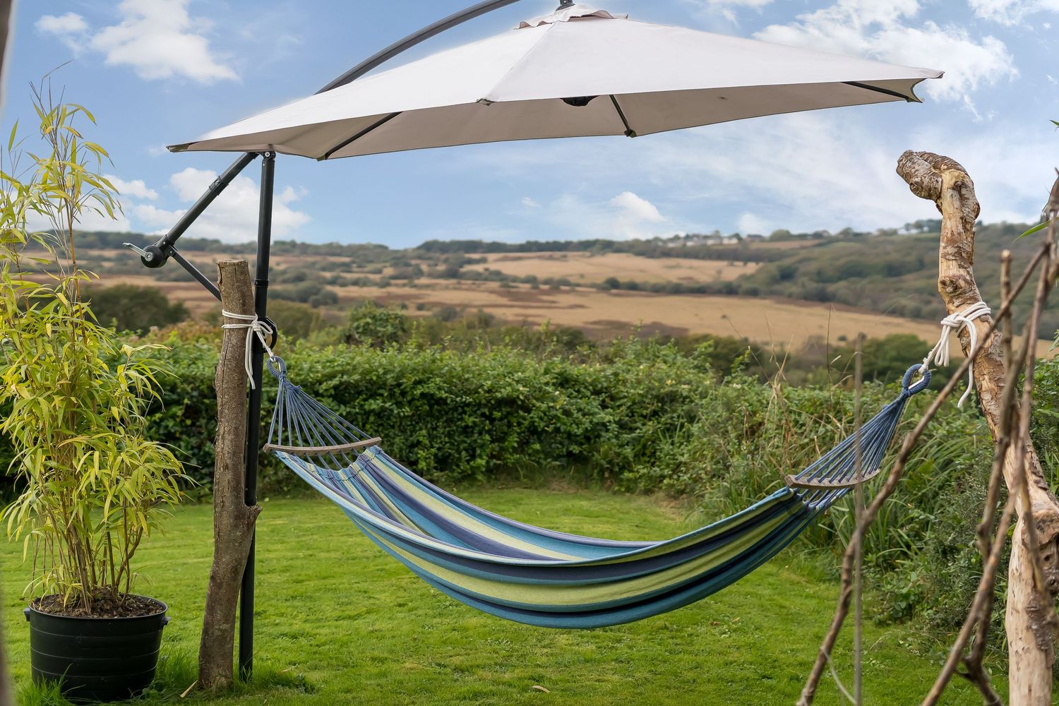 Hammock with umbrella shade overlooking rolling countryside hills.