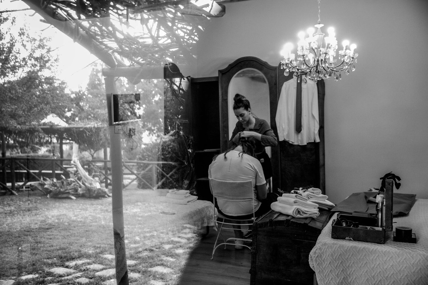 Black and white image of a salon interior with chair, mirror, and chandelier creating an elegant atmosphere.