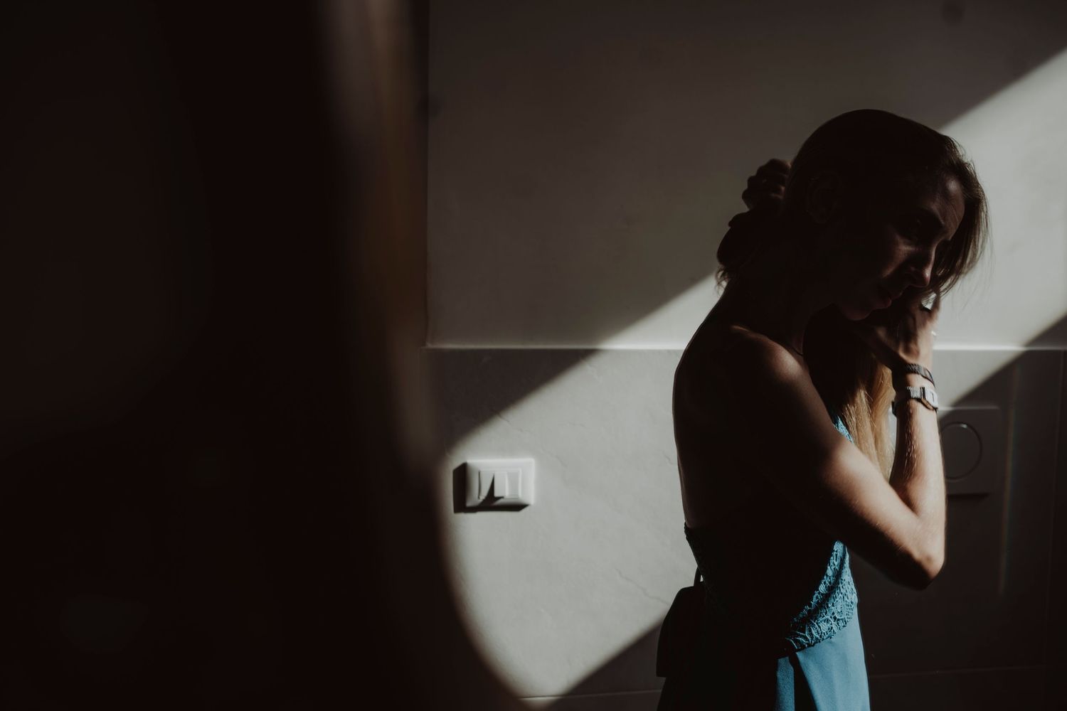 Silhouette figure stands in dramatic lighting with shadow cast on wall.