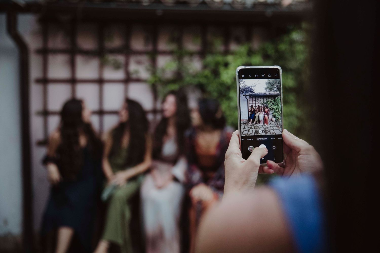 Someone taking a photo of a group with a smartphone at an outdoor gathering.