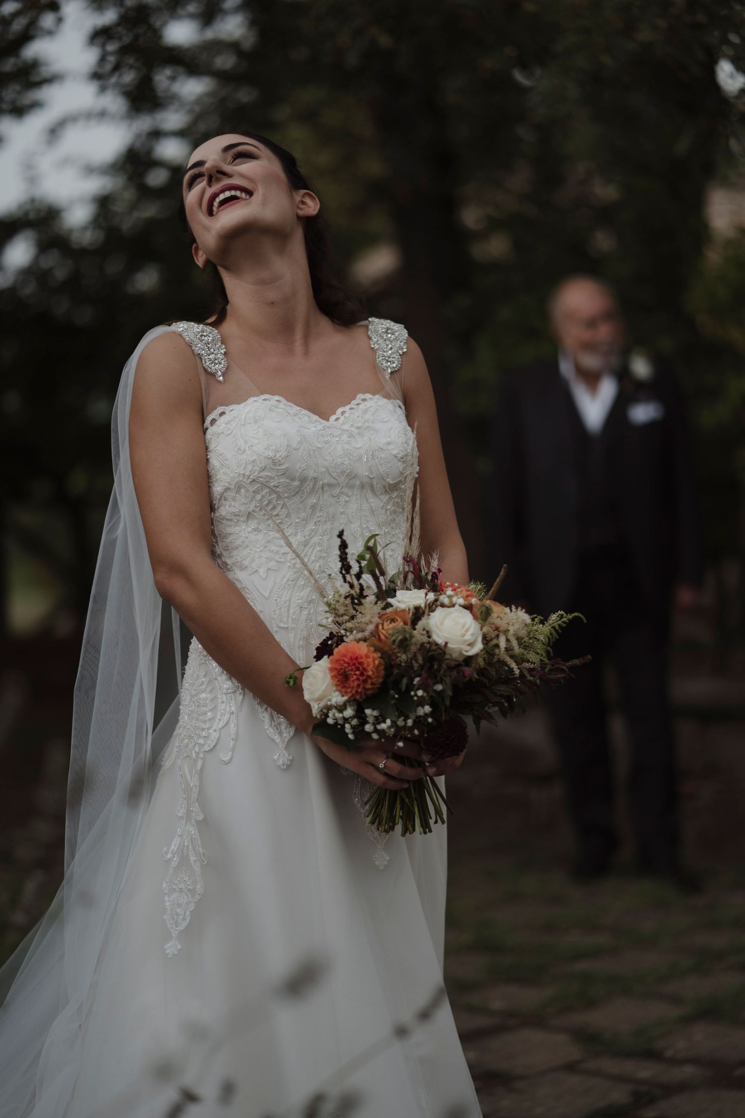 Joyful moment captured in white wedding dress with bouquet outdoors.