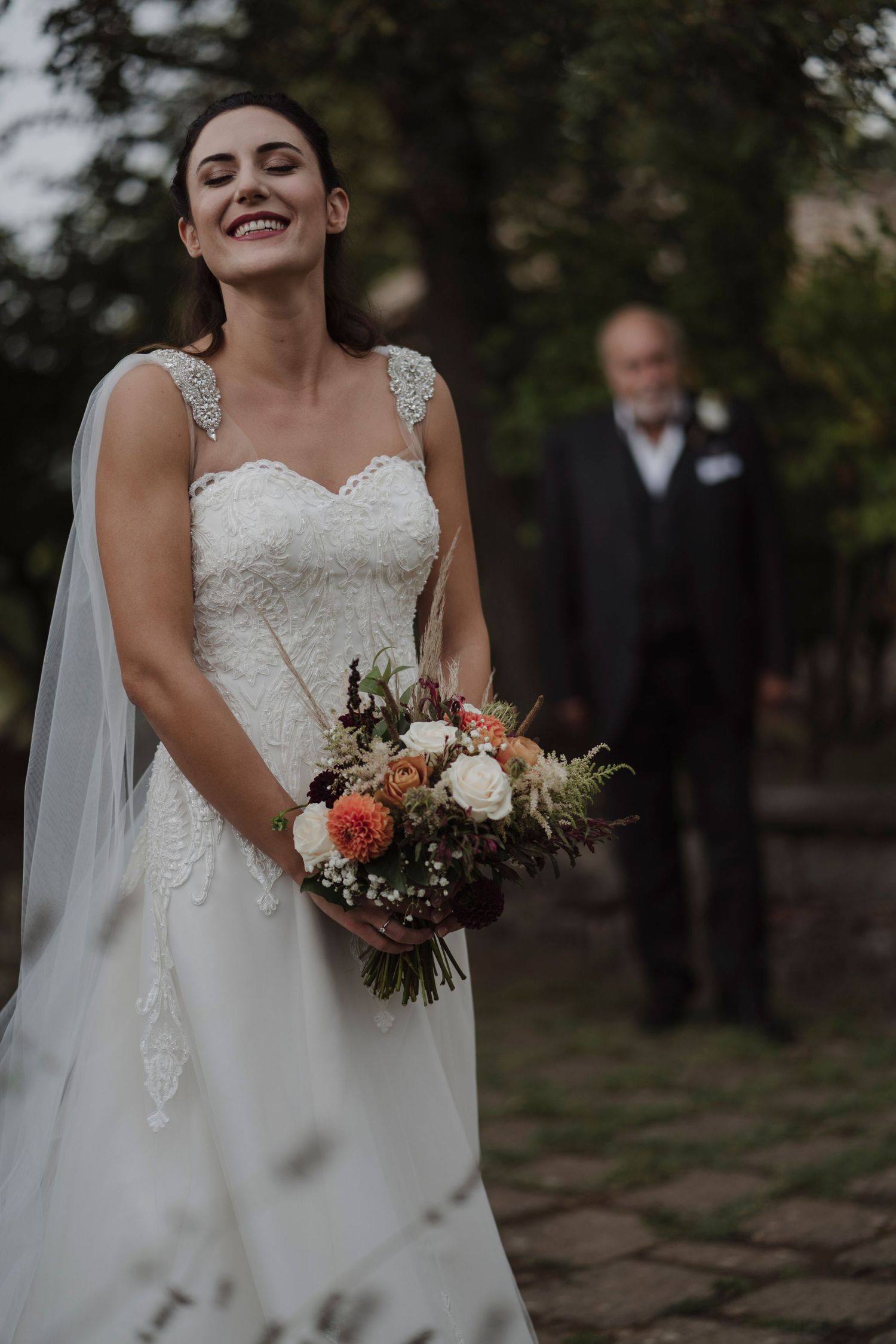 Candid moment of joy with beautiful floral bouquet and white wedding dress.