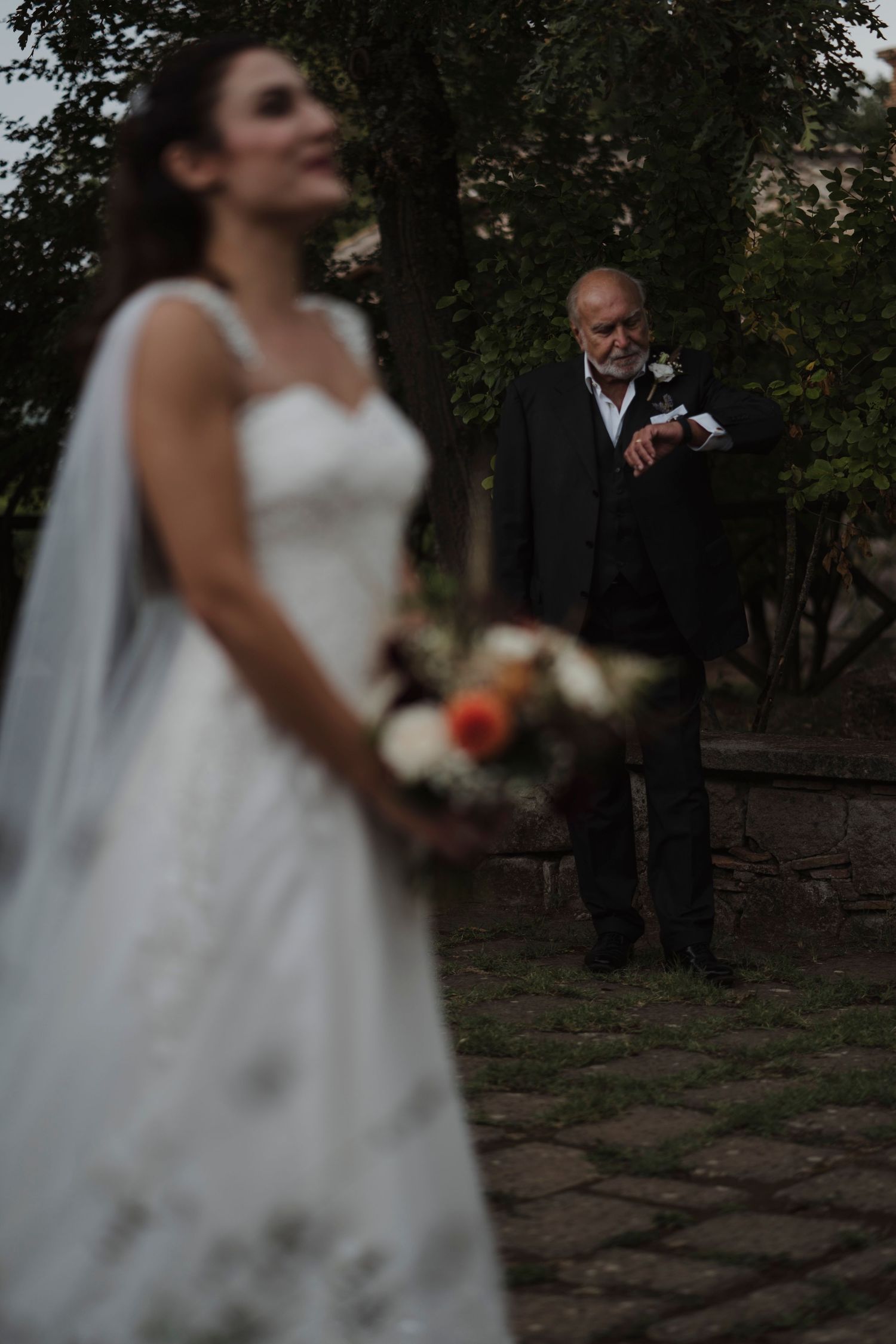 Artistic wedding photo composition on stone pathway with dress and bouquet in focus.