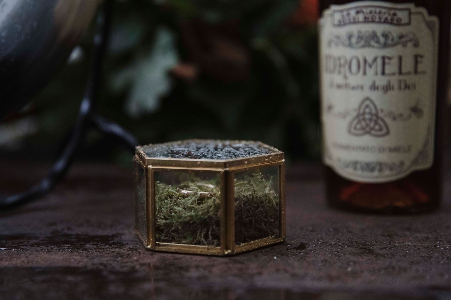A decorative glass box sits near a vintage bottle on a dark wooden surface.